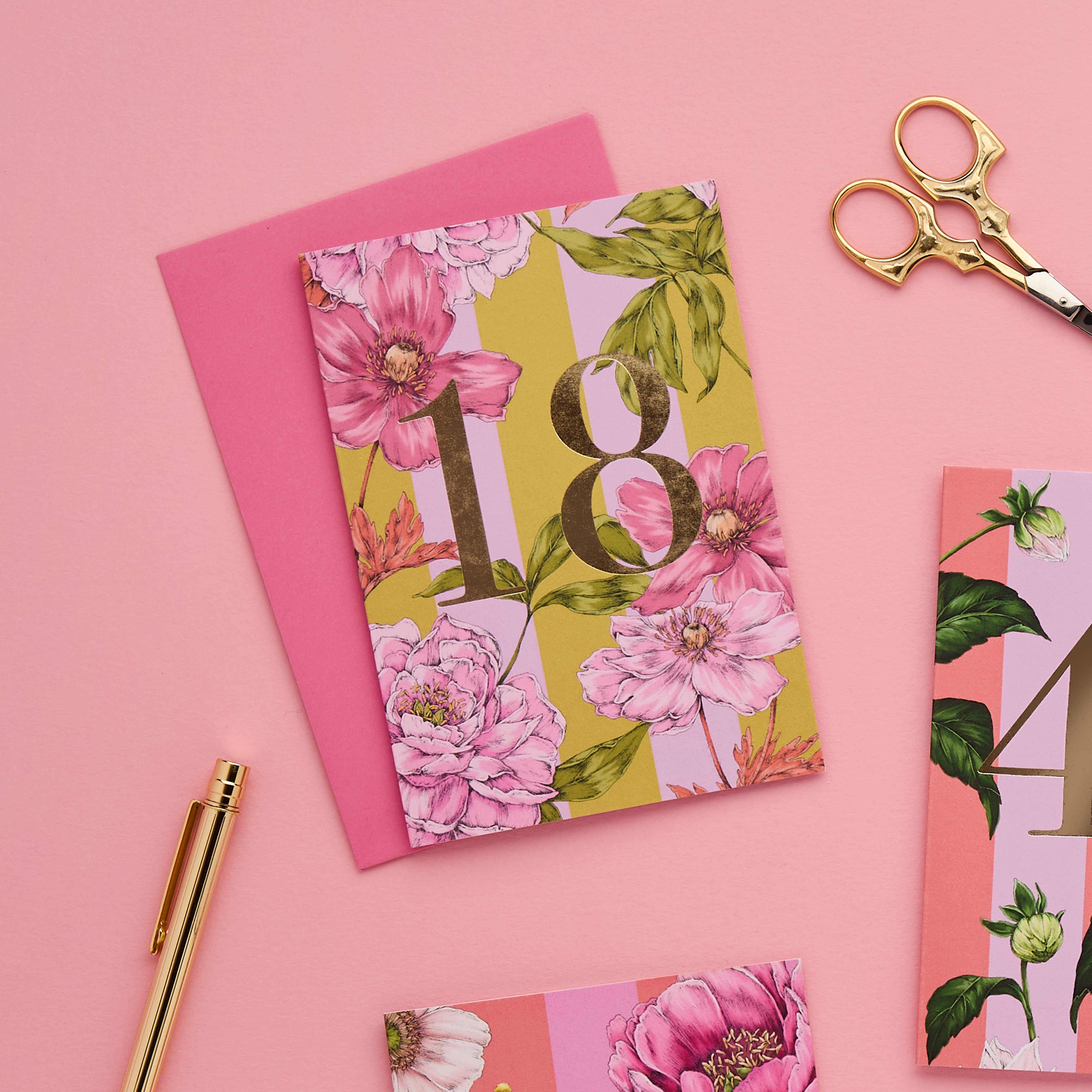 Floral card with number 18 on a pink background with scissors and pen.