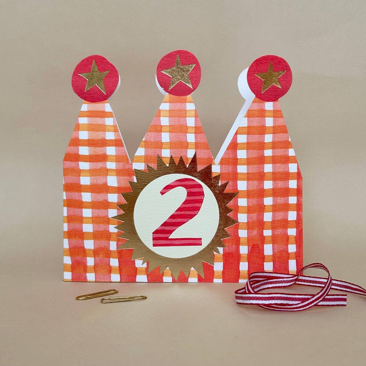 Decorative birthday hat with number 2 on a beige background.