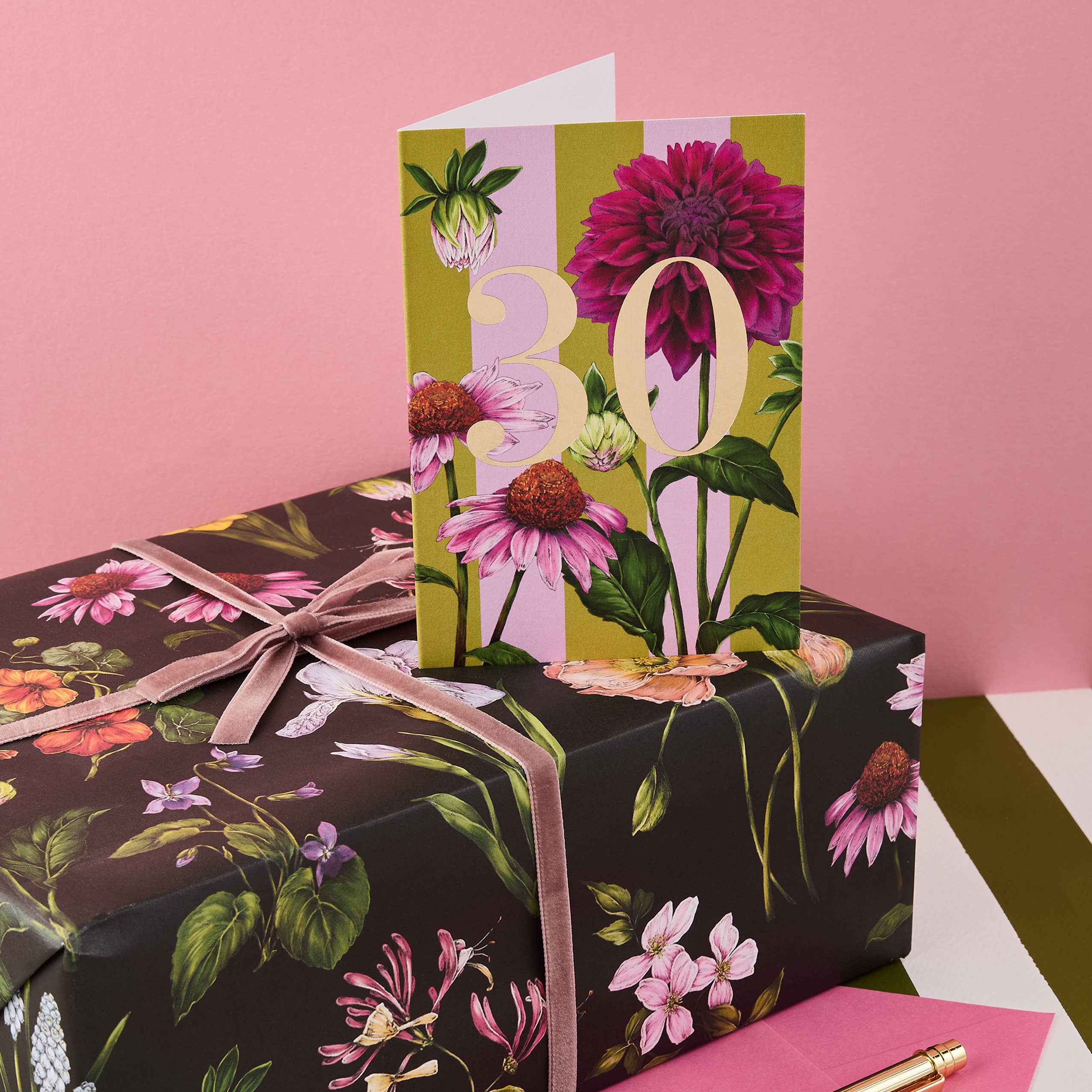 Floral-patterned gift box with a matching card on a pink background.