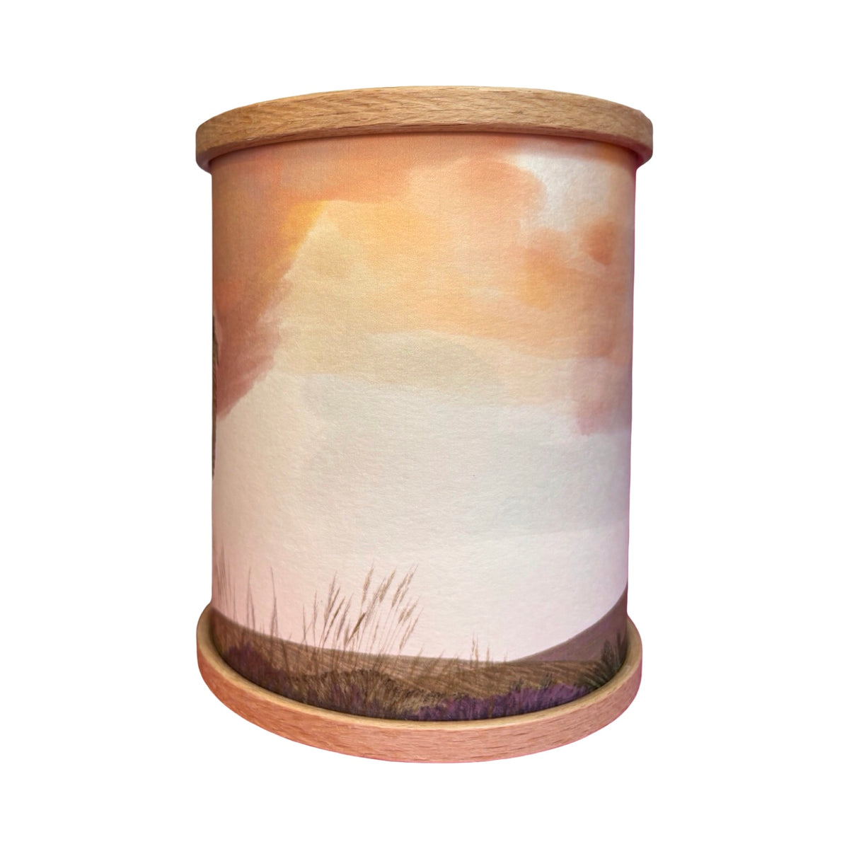 A cylindrical wooden candle holder featuring a printed watercolour landscape design in soft peach, orange, cream, and purple tones, set against a plain white background.