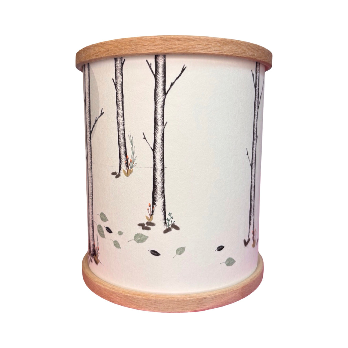 A cylindrical candle holder with a light wood rim and base, featuring a woodland illustration of birch trees and leaves.