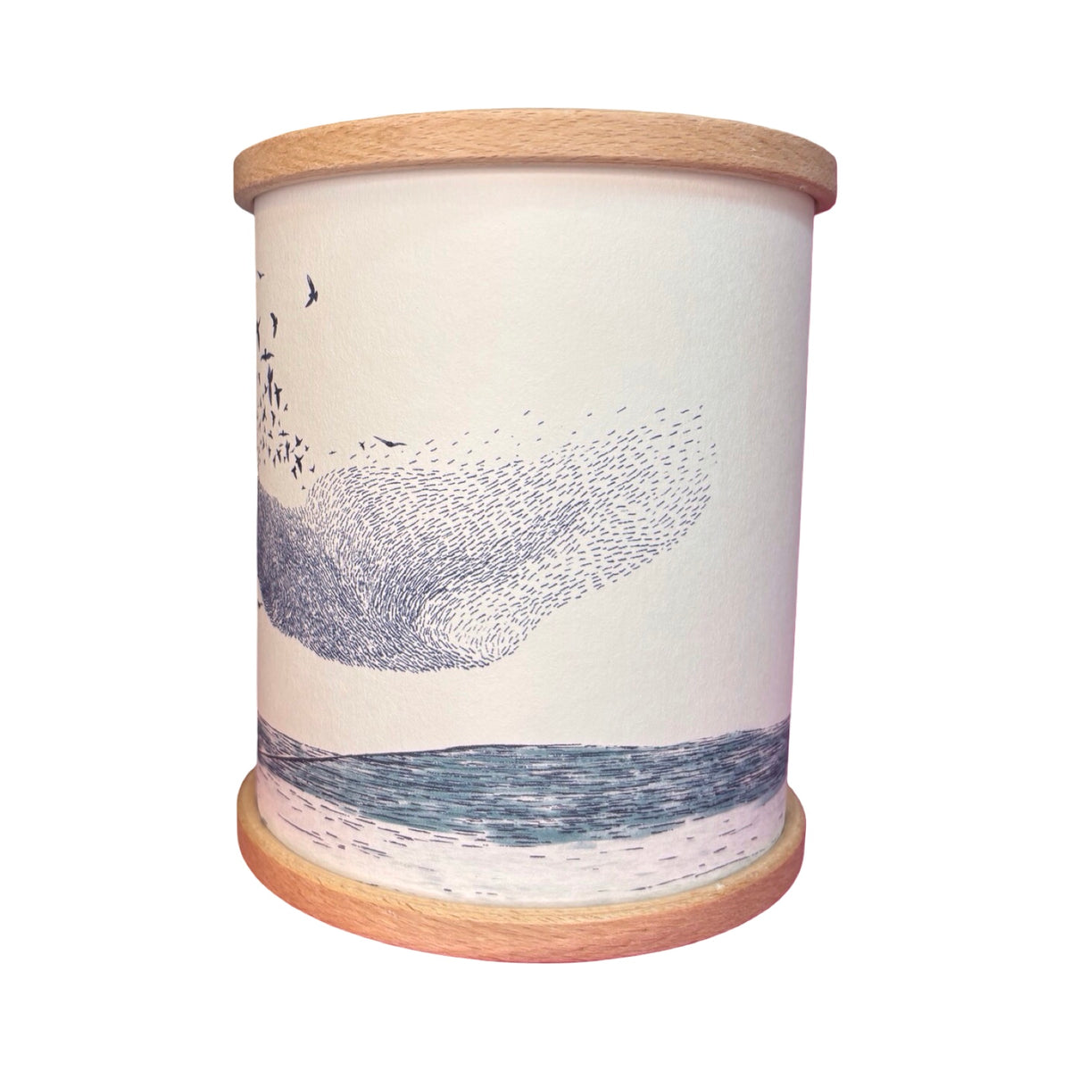 A cylindrical candle holder with a light wood rim and base, featuring an illustration of a murmuration of birds over the ocean.