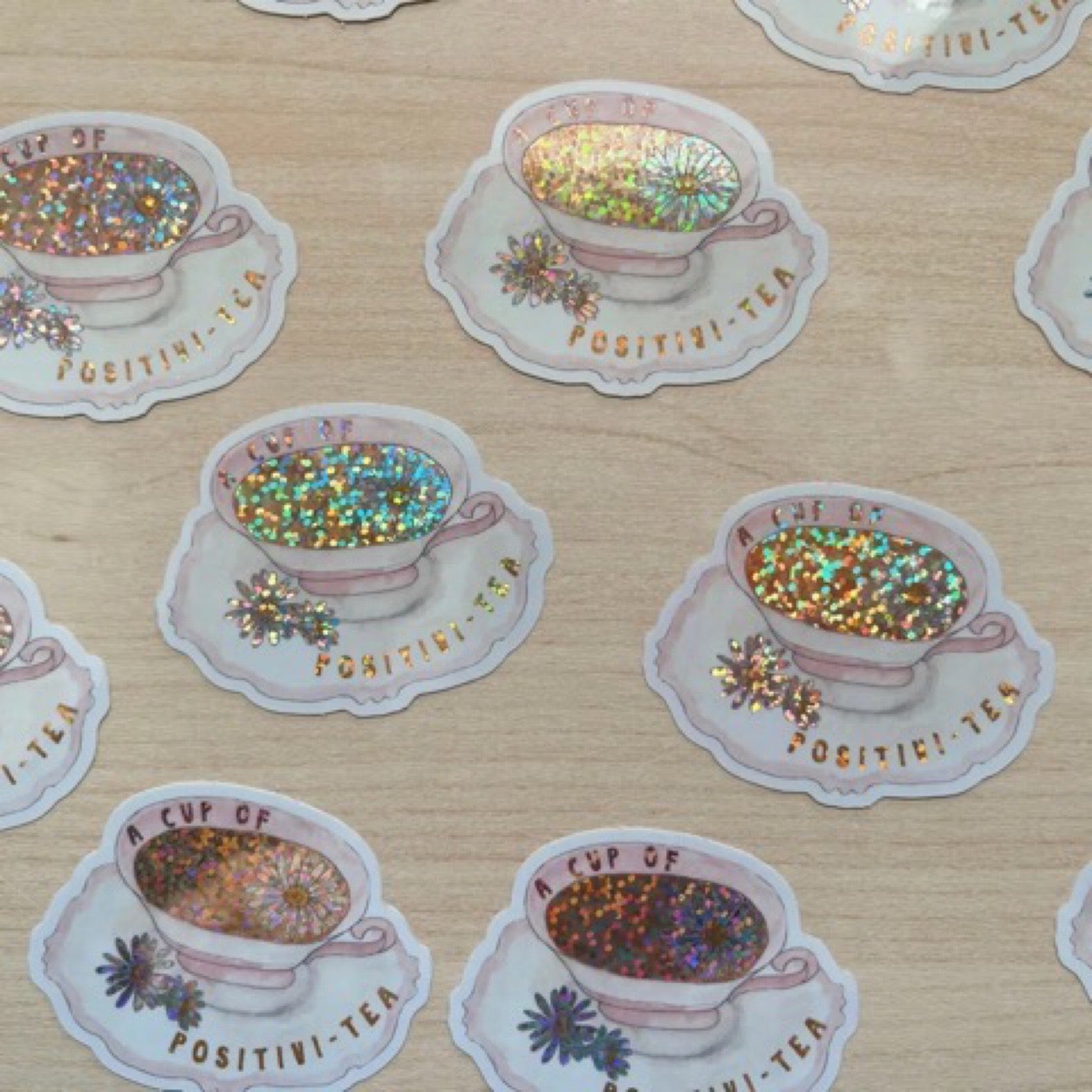 A waterproof vinyl sticker shaped like a teacup and saucer with the text 'A Cup of Positivi-tea'.
