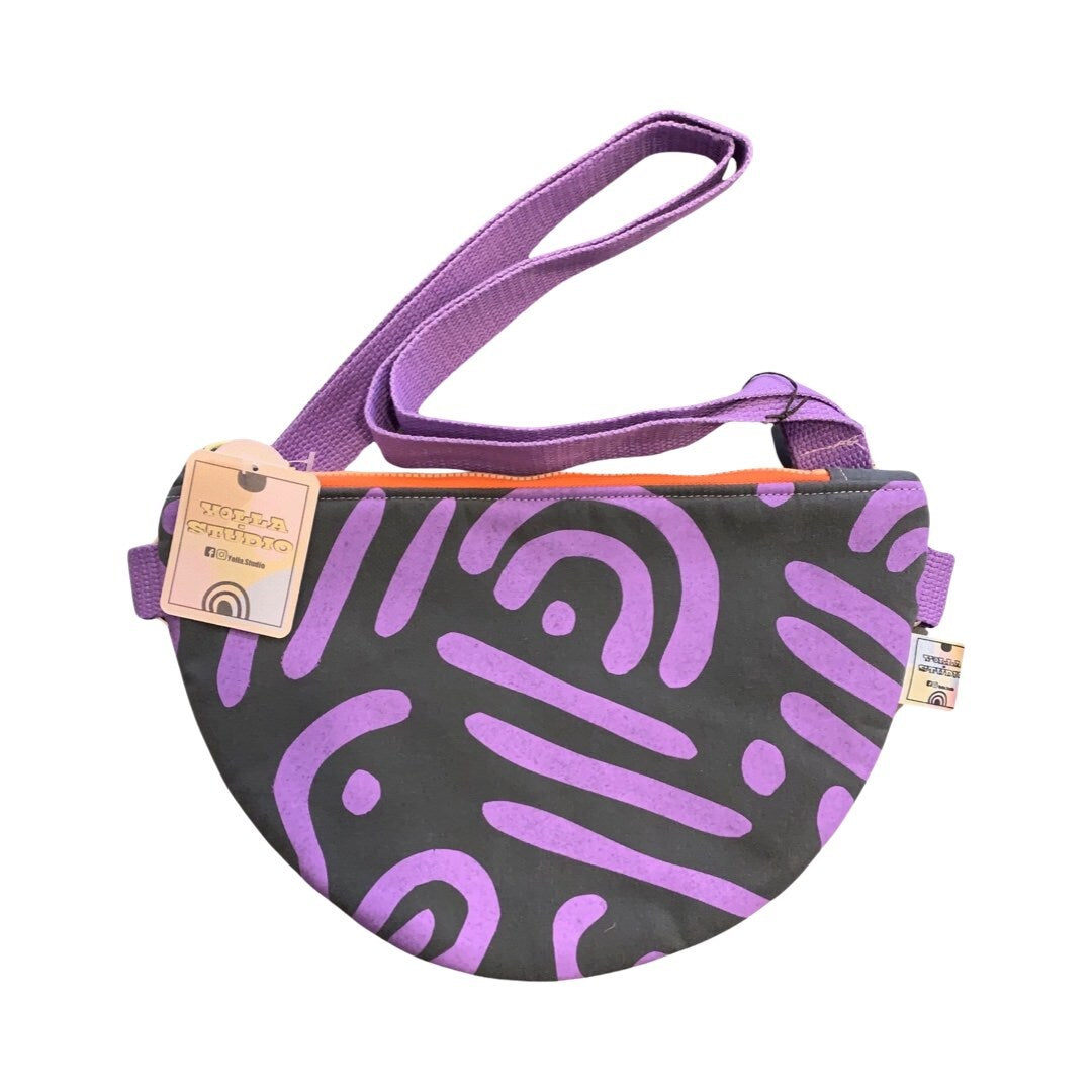 a purple and grey cross-body bag in an abstract design with an adjustable strap.