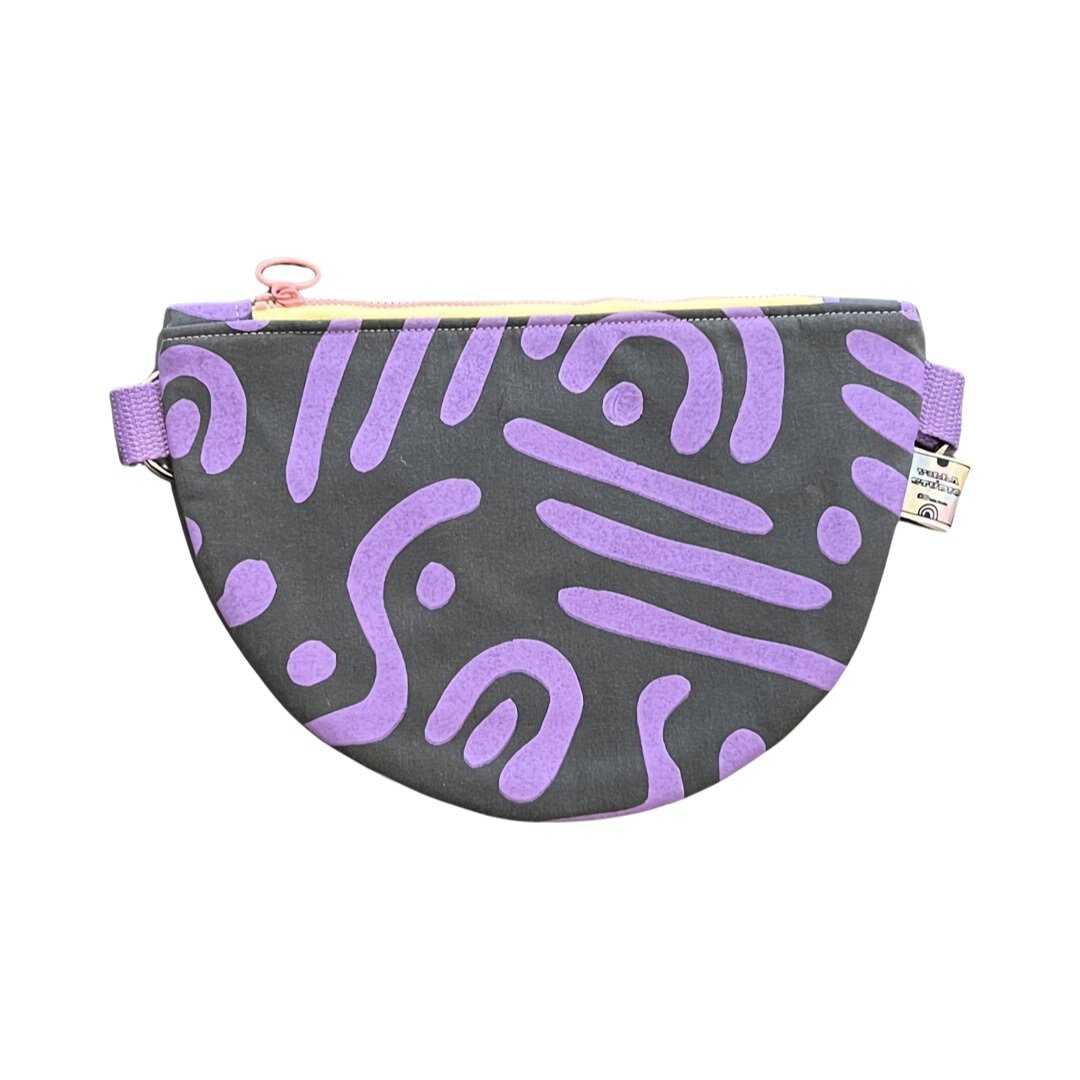 a purple and grey cross-body bag in an abstract design.
