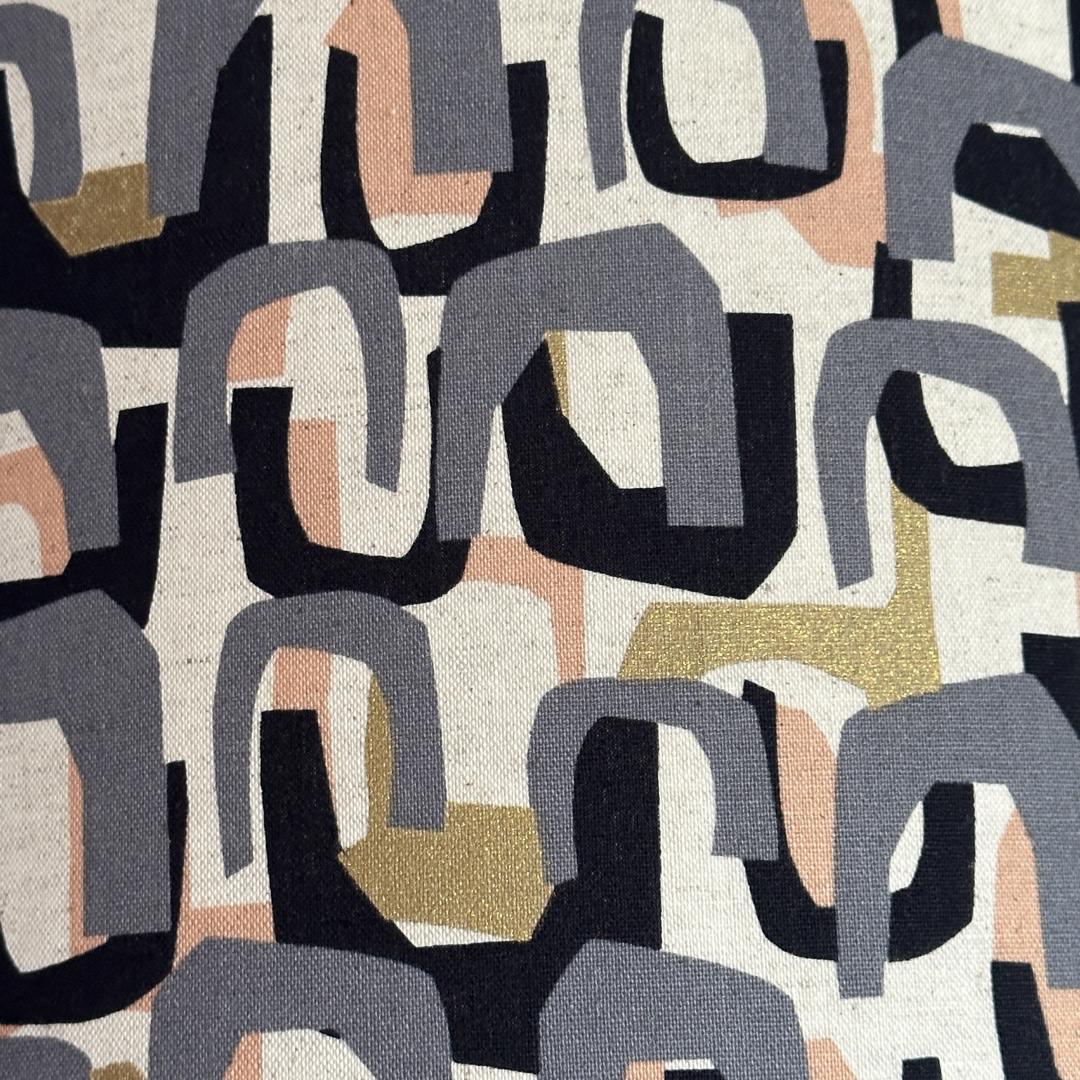 Fabric with a grey, peach, black and gold arch pattern.