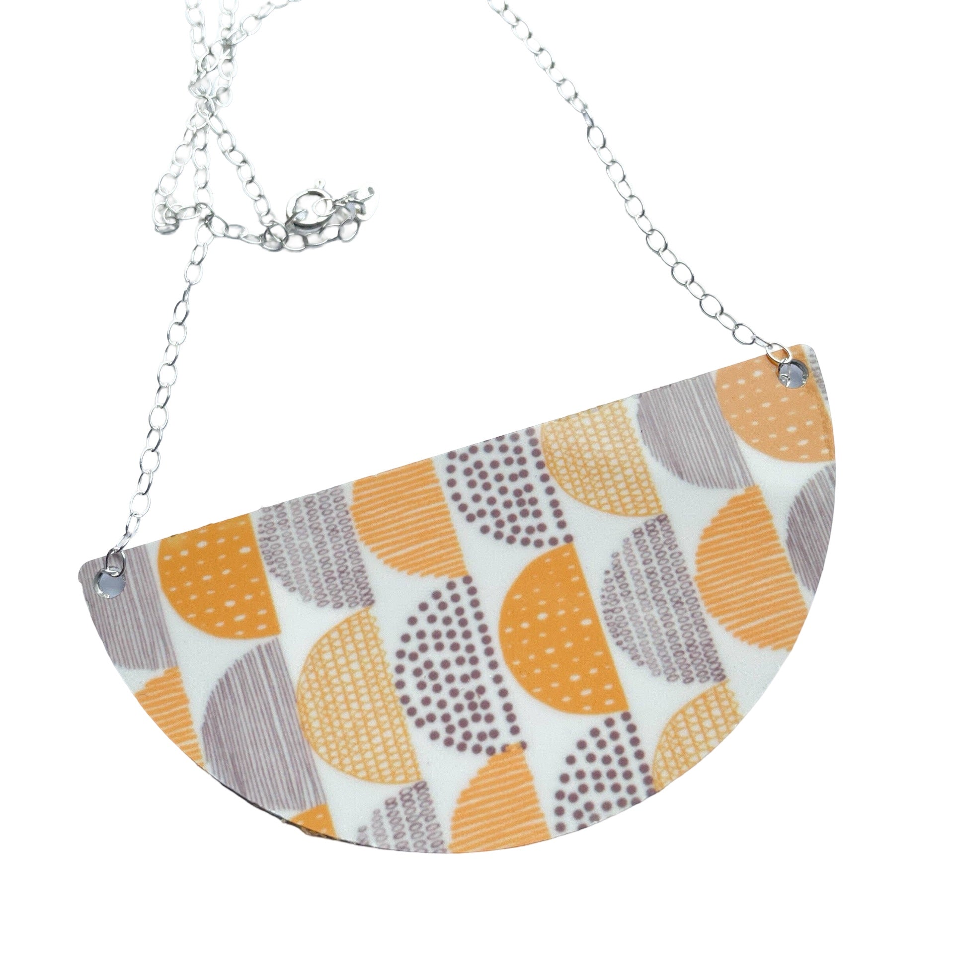 Hand-printed aluminium arc-shaped necklace with grey and mustard patterned arcs on a cream background hung on a Sterling Silver 18" chain.