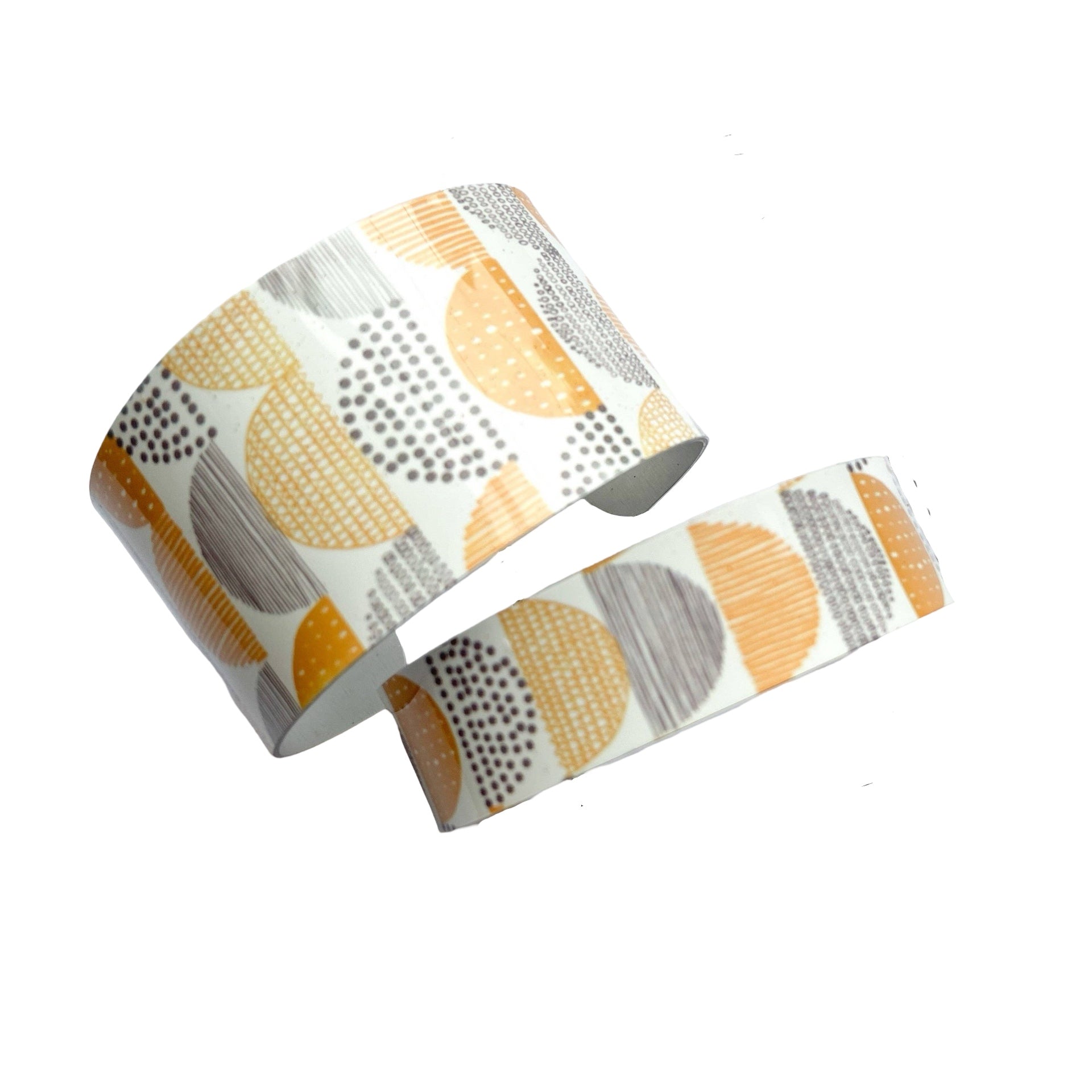 The statement cuff bracelet features a mustard and grey arcs design on a cream background.