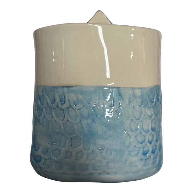 The back of a handmade ceramic pot with teal mermaid scales.