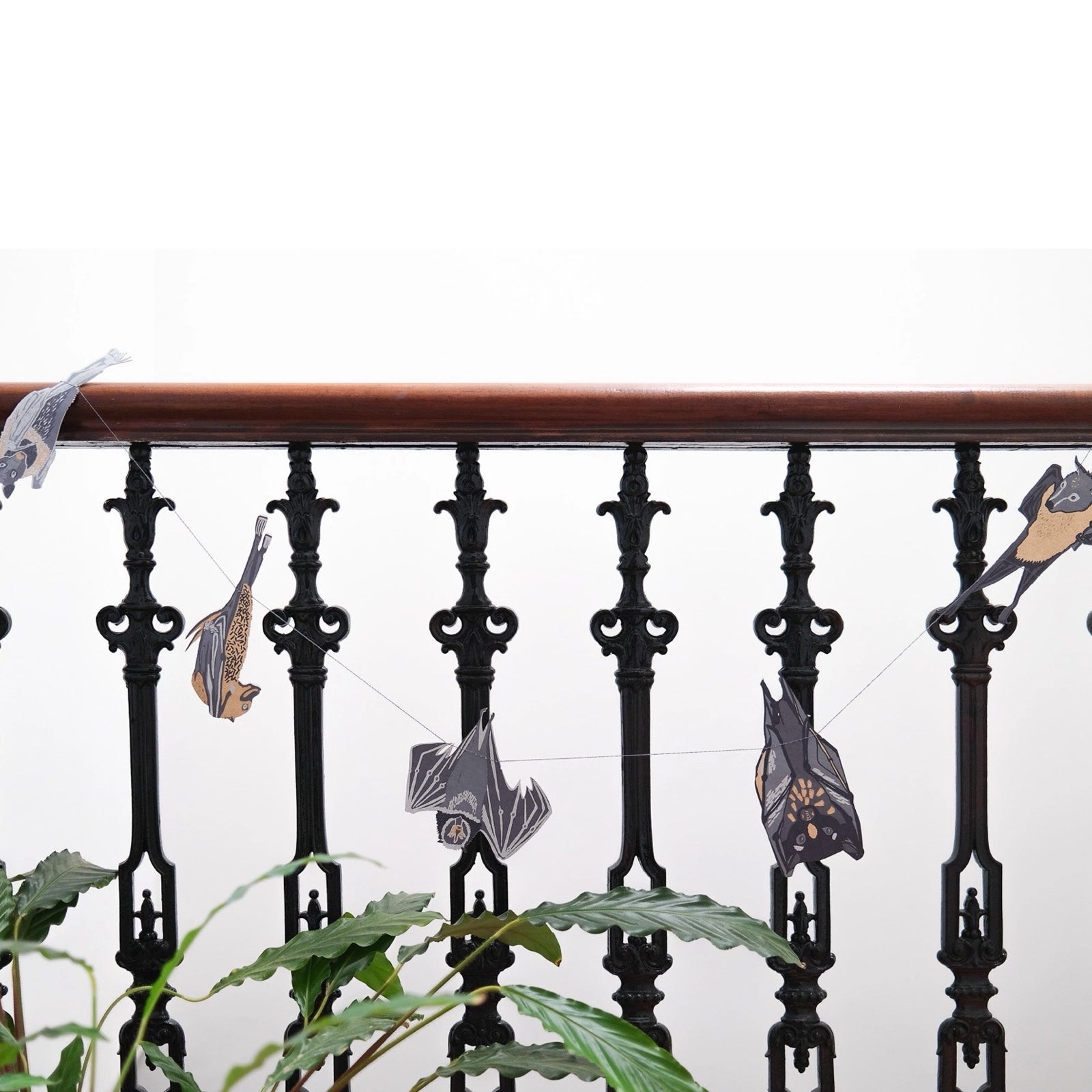 Bats paper garland featuring twelve screen-printed paper bats in black, grey and cream hanging on a black metal banister.