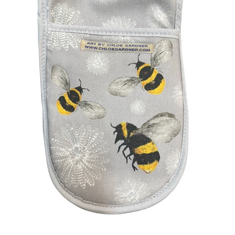 Grey oven gloves featuring flying bees and white flowers.