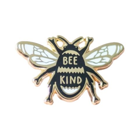 Bee-shaped enamel pin badge. in black, white and gold with the text 'Bee Kind'.