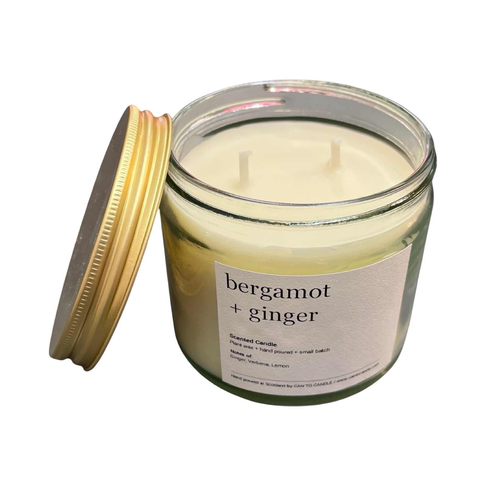Candle jar labeled 'bergamot + ginger' with a gold lid on a white background.