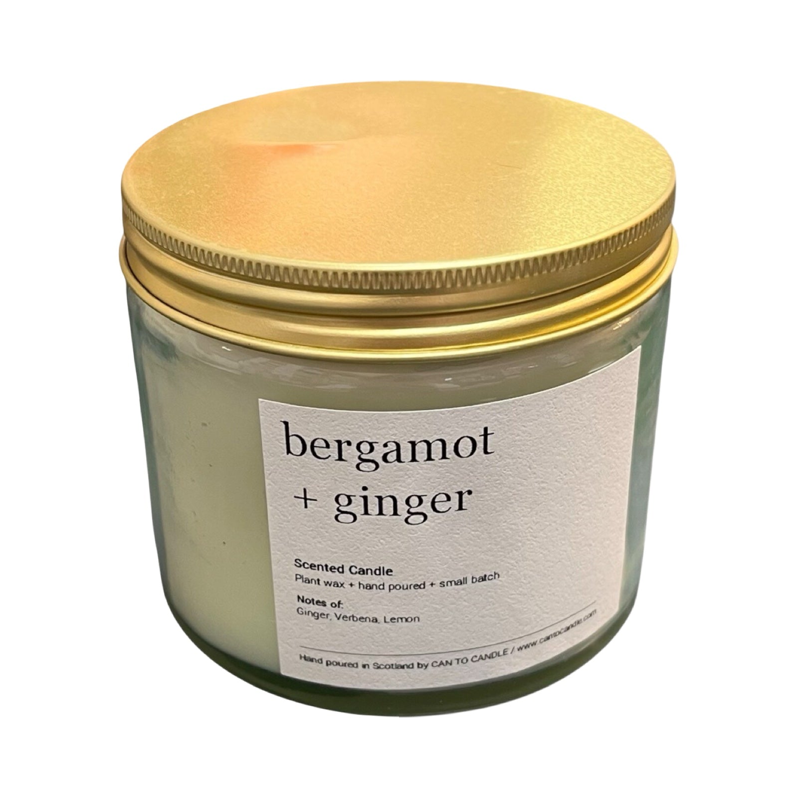 Scented candle with gold lid labeled 'bergamot + ginger' on a white background.