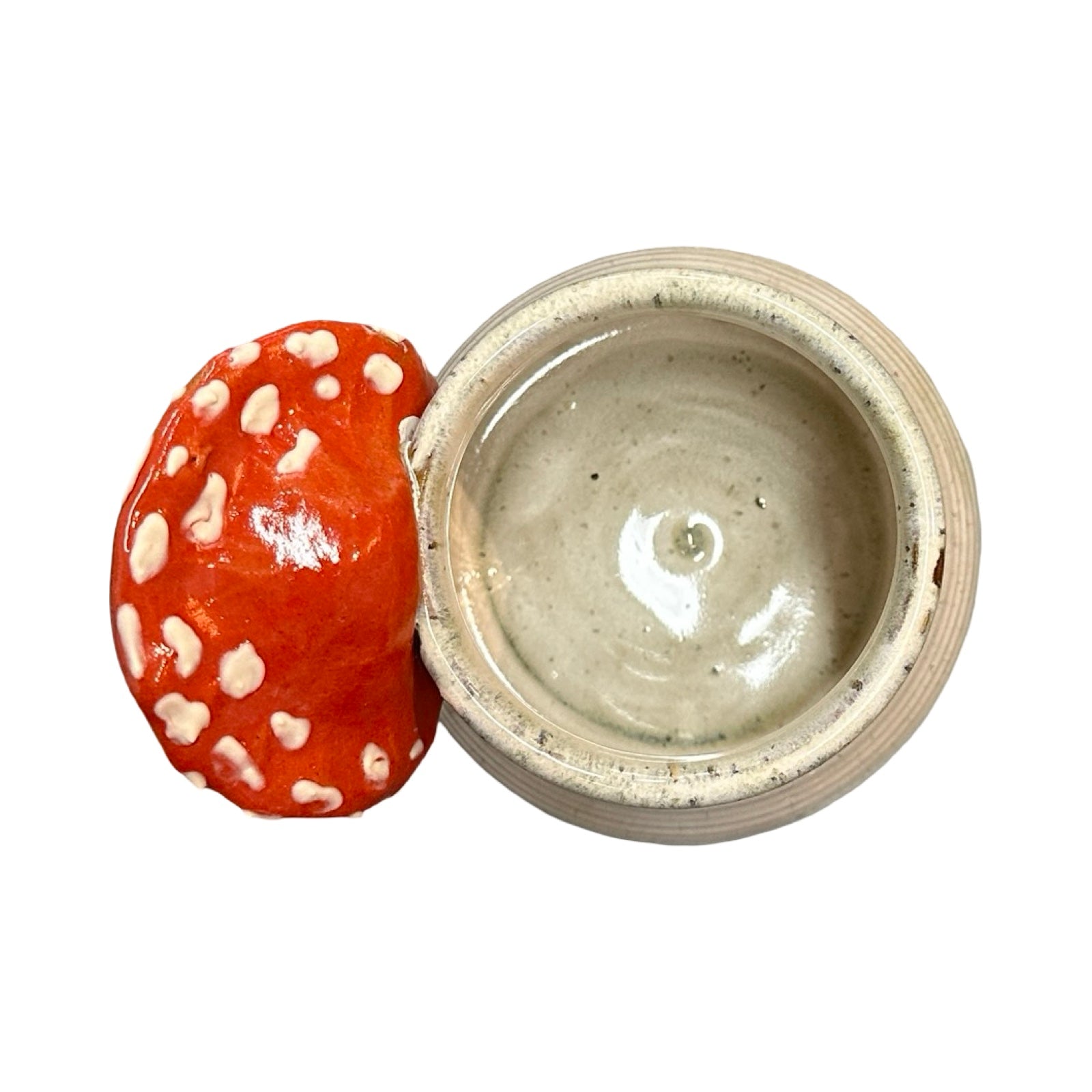 Ceramic mug with a red and white mushroom handle on a white background.