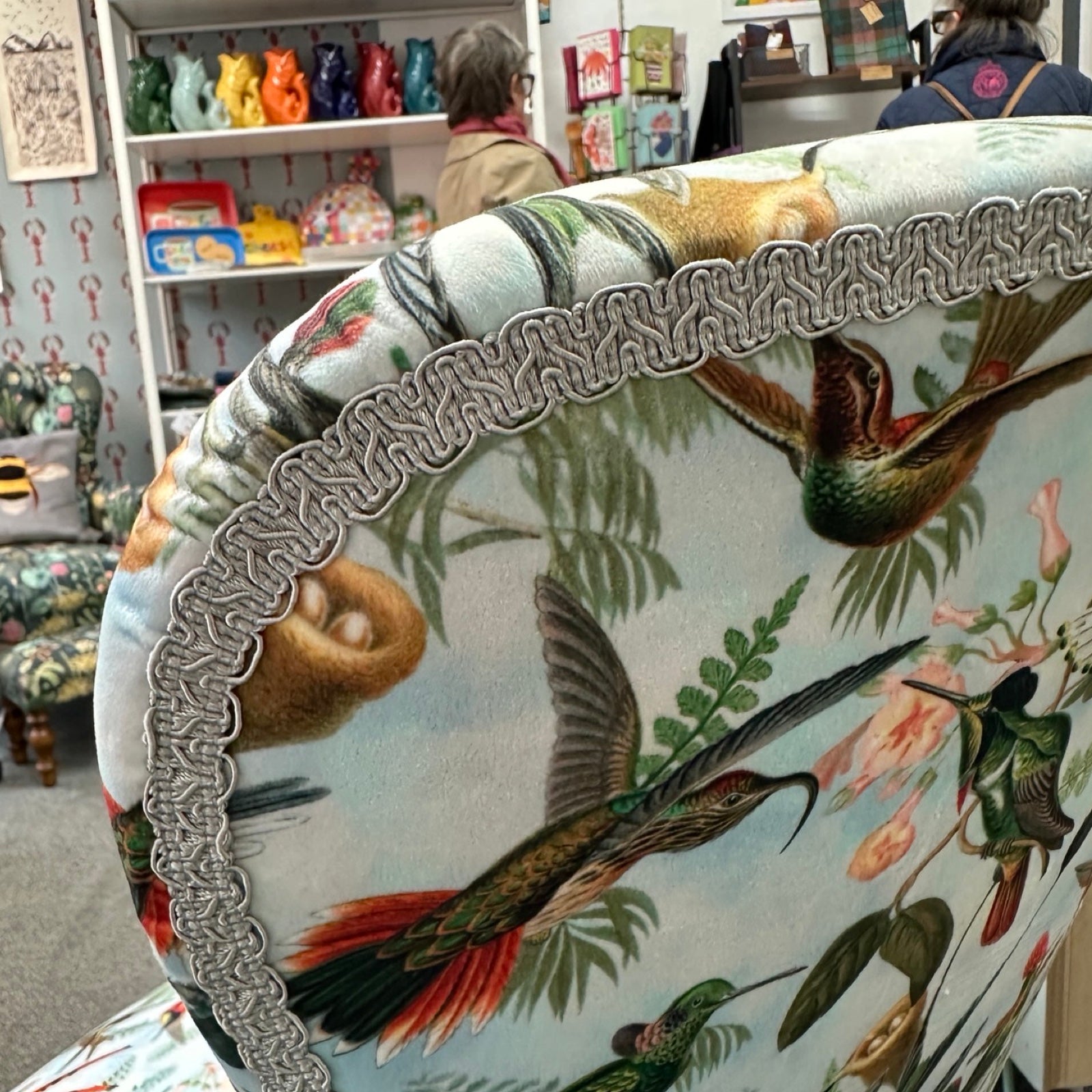 Decorative cushion with bird and floral pattern in a store.