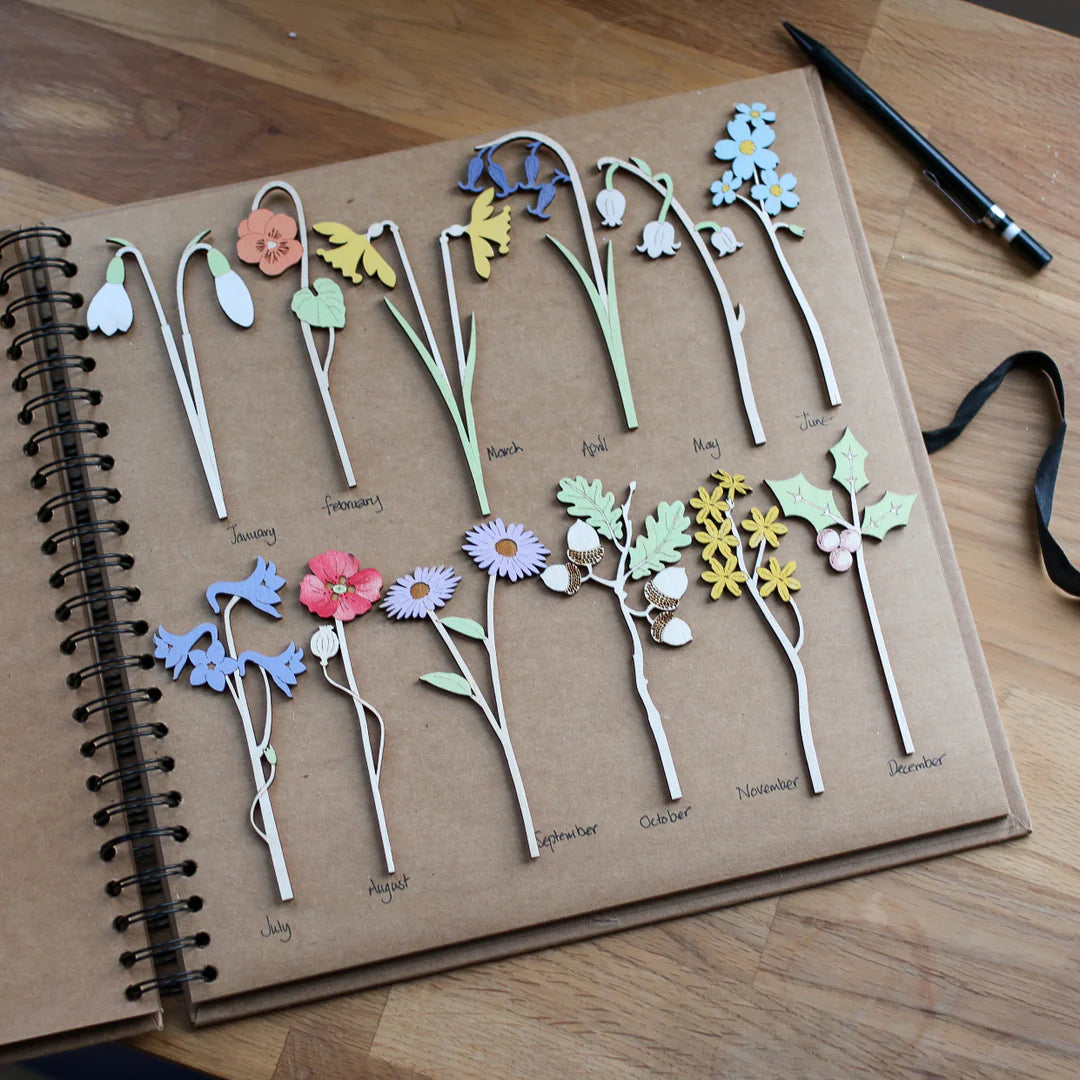 A brown paper book with colourful wooden flowers next to their month.