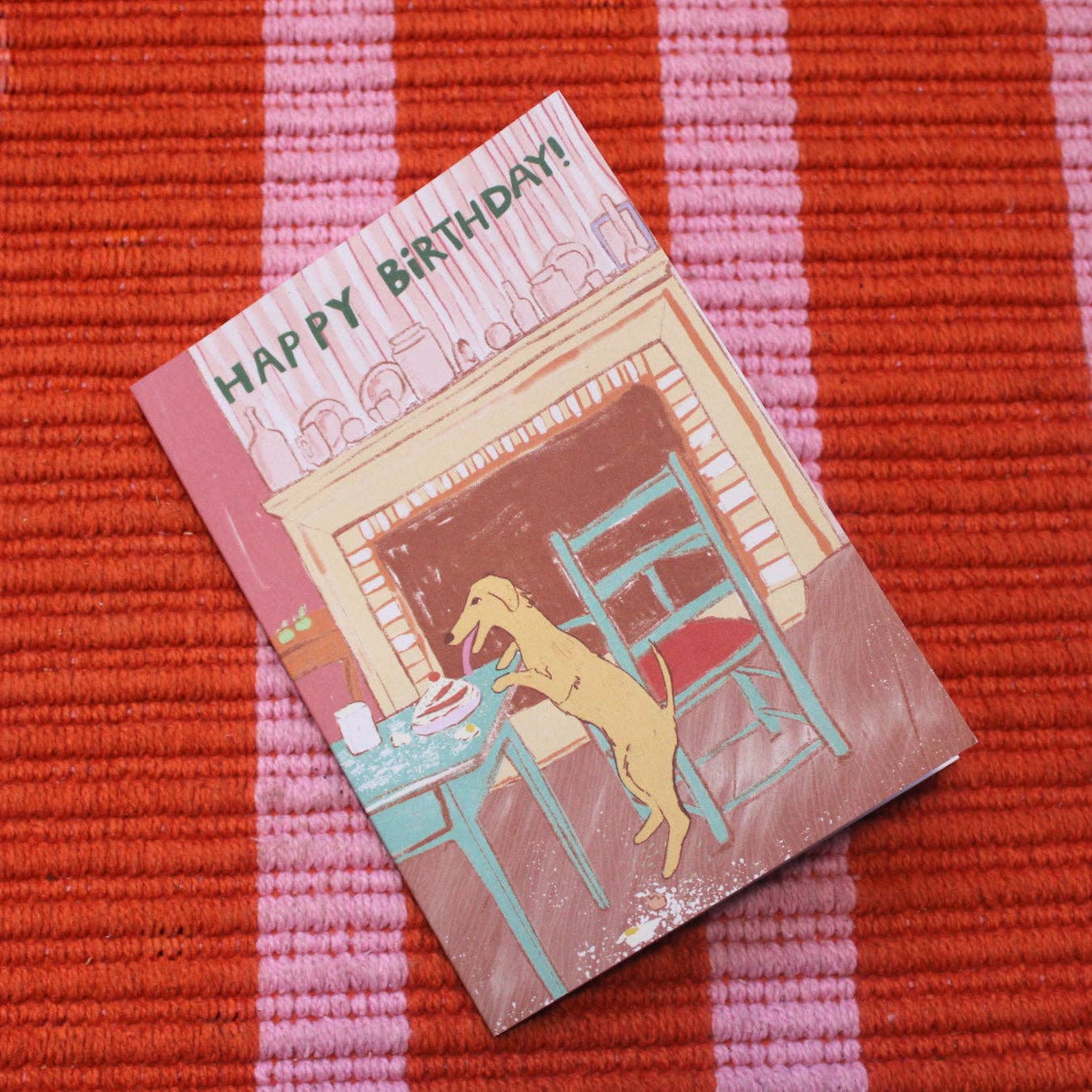 Birthday card with a dog illustration on a red and pink striped background.