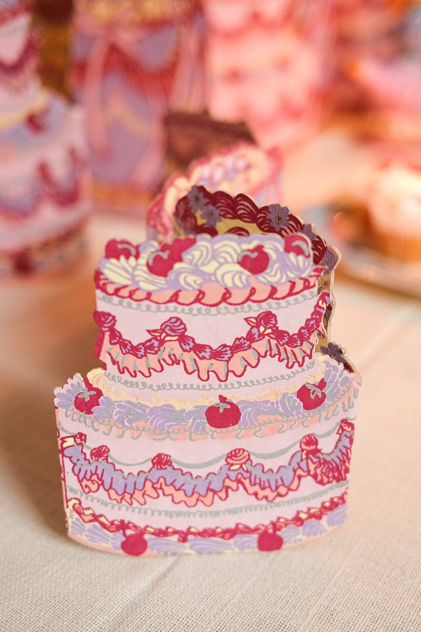 Decorative paper cake with pink and purple details on a neutral background.
