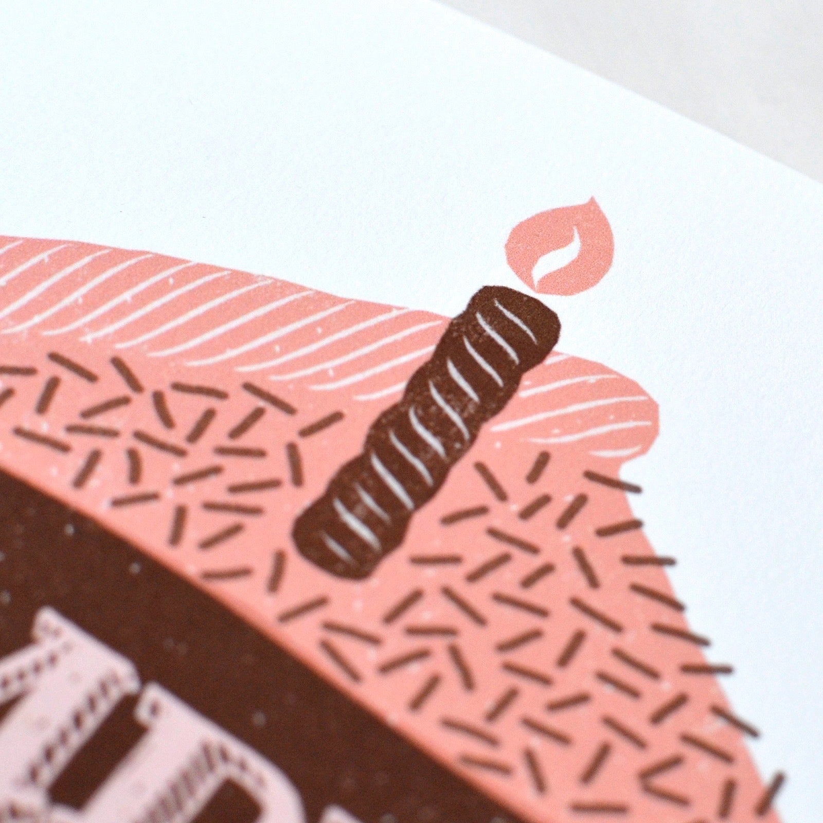 Illustration of a cake with pink frosting and chocolate decorations on a white background.