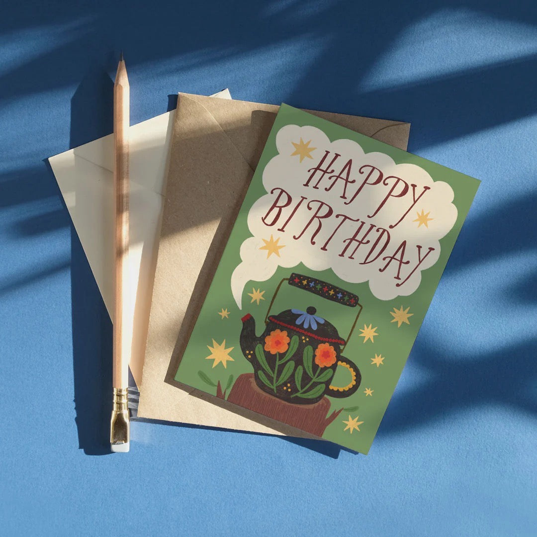 Birthday card with teapot illustration on a blue background.