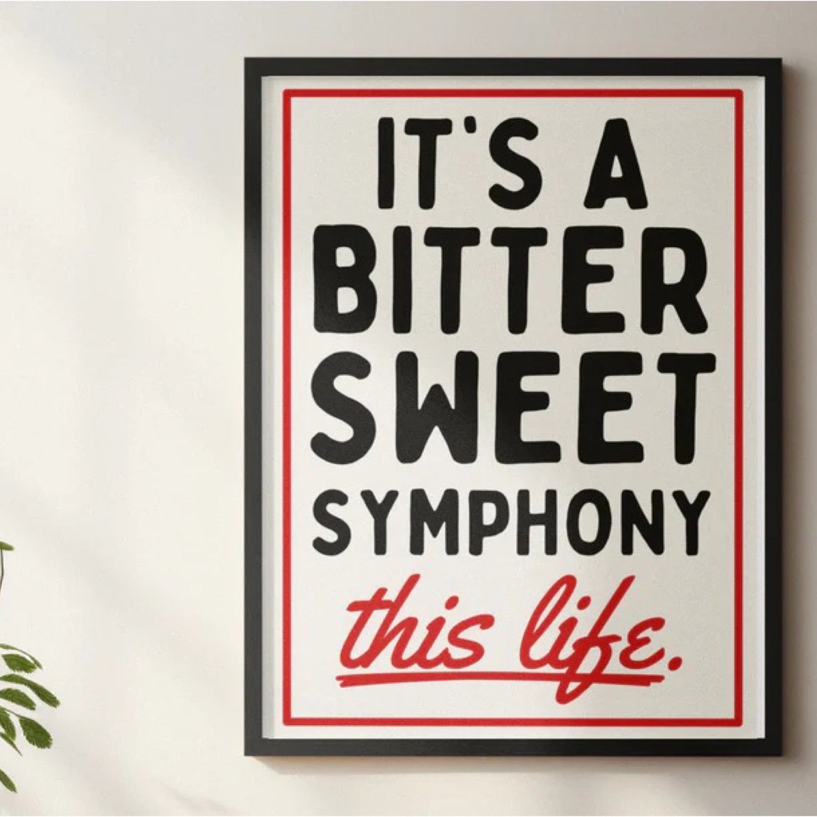 Framed poster with text 'It's a bitter sweet symphony this life' on a white wall.