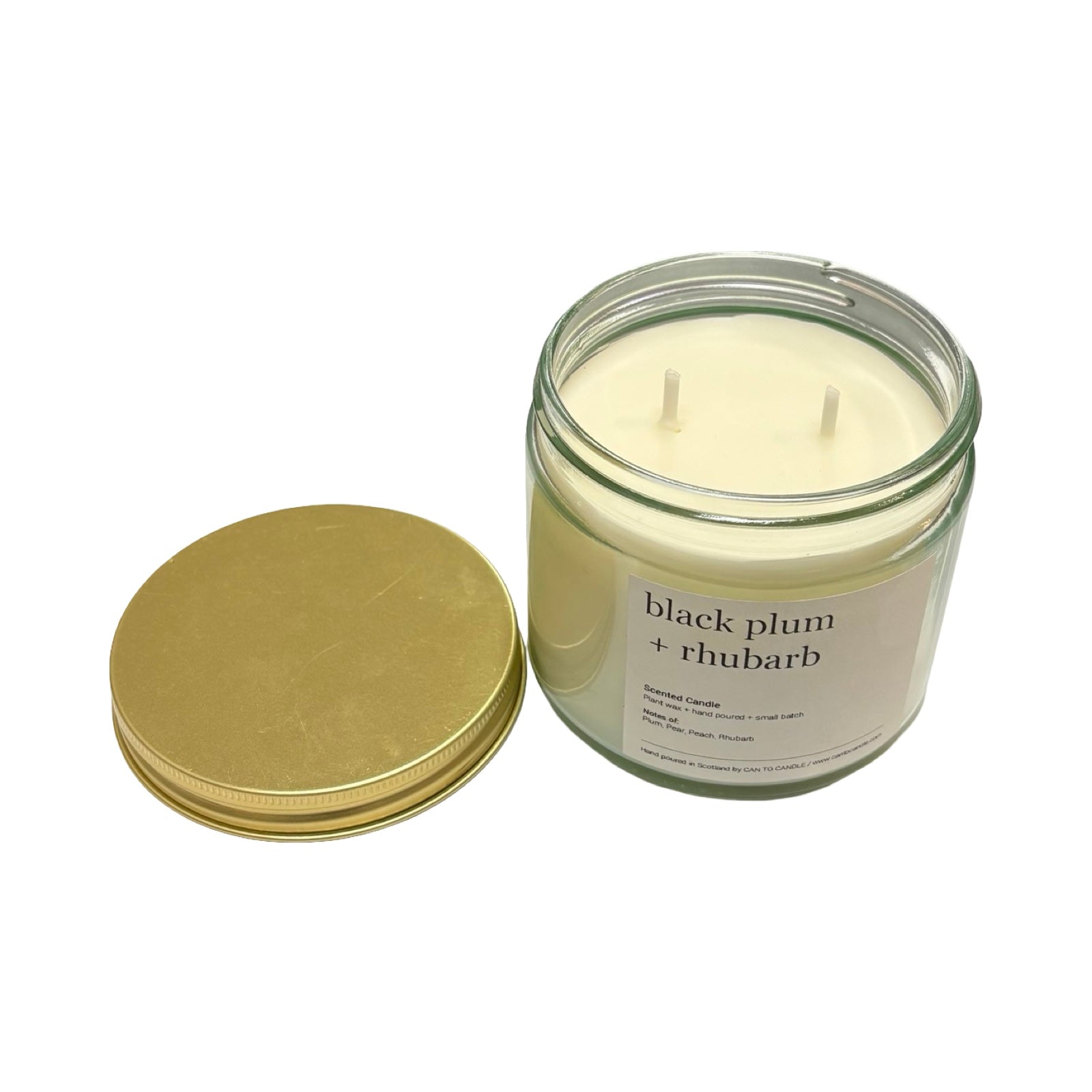 Glass candle jar with gold lid labeled 'black plum + rhubarb' on a white background.