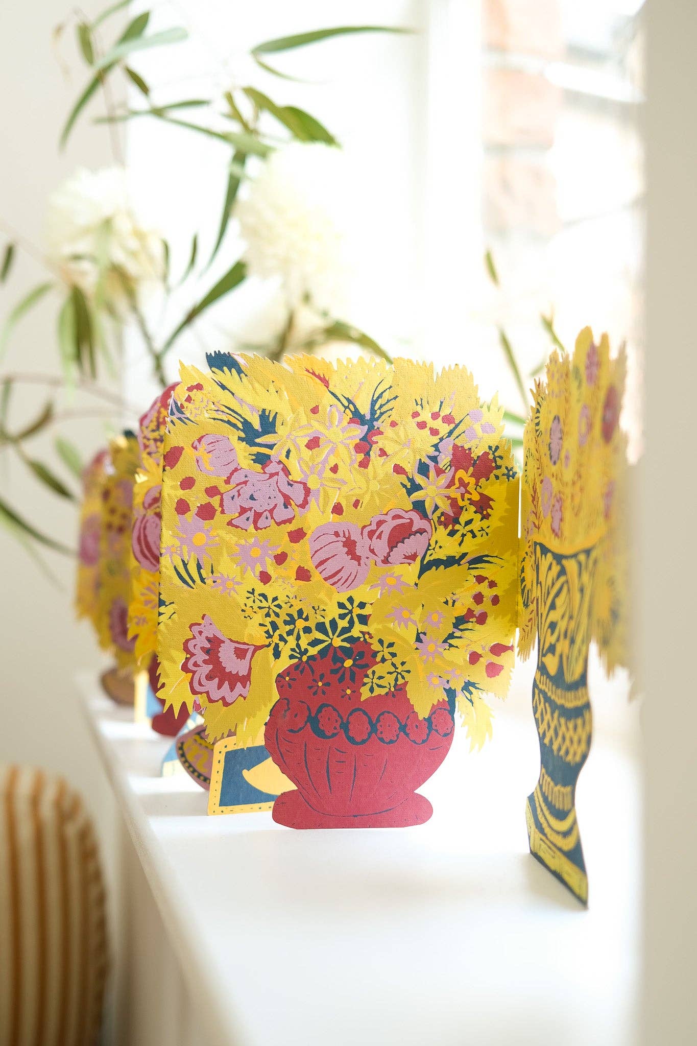 Colourful paper flower with floral patterns on a white surface.