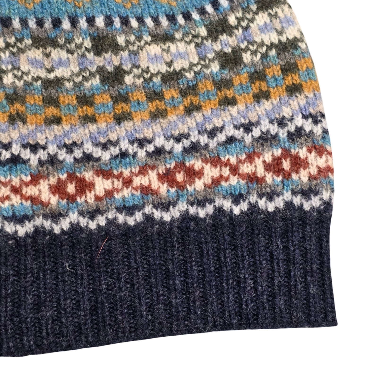 Close-up of a knitted fabric with a multicolor pattern on a white background.