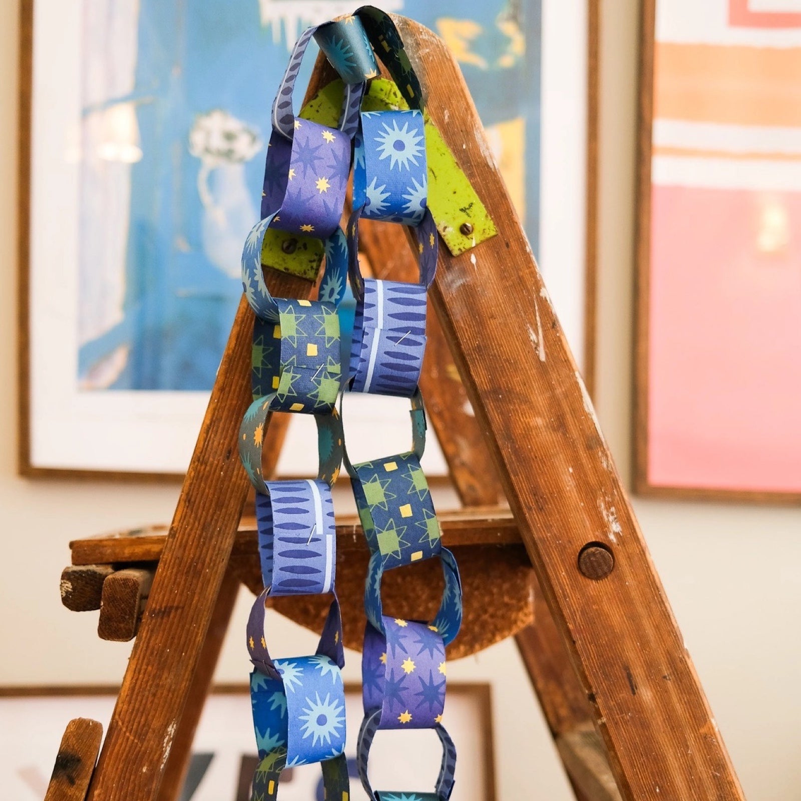 A paper chain made from blue paper with yellow stars, blue paper with light blue stars and light blue paper with blue ovals.