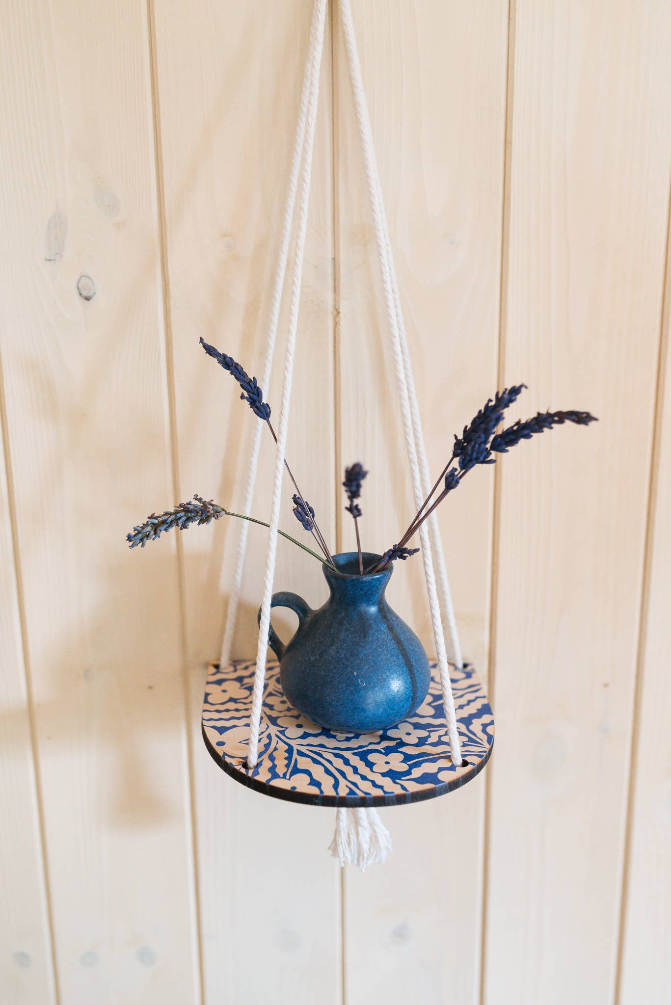 Hanging ceramic pot with dried lavender on a wooden background.