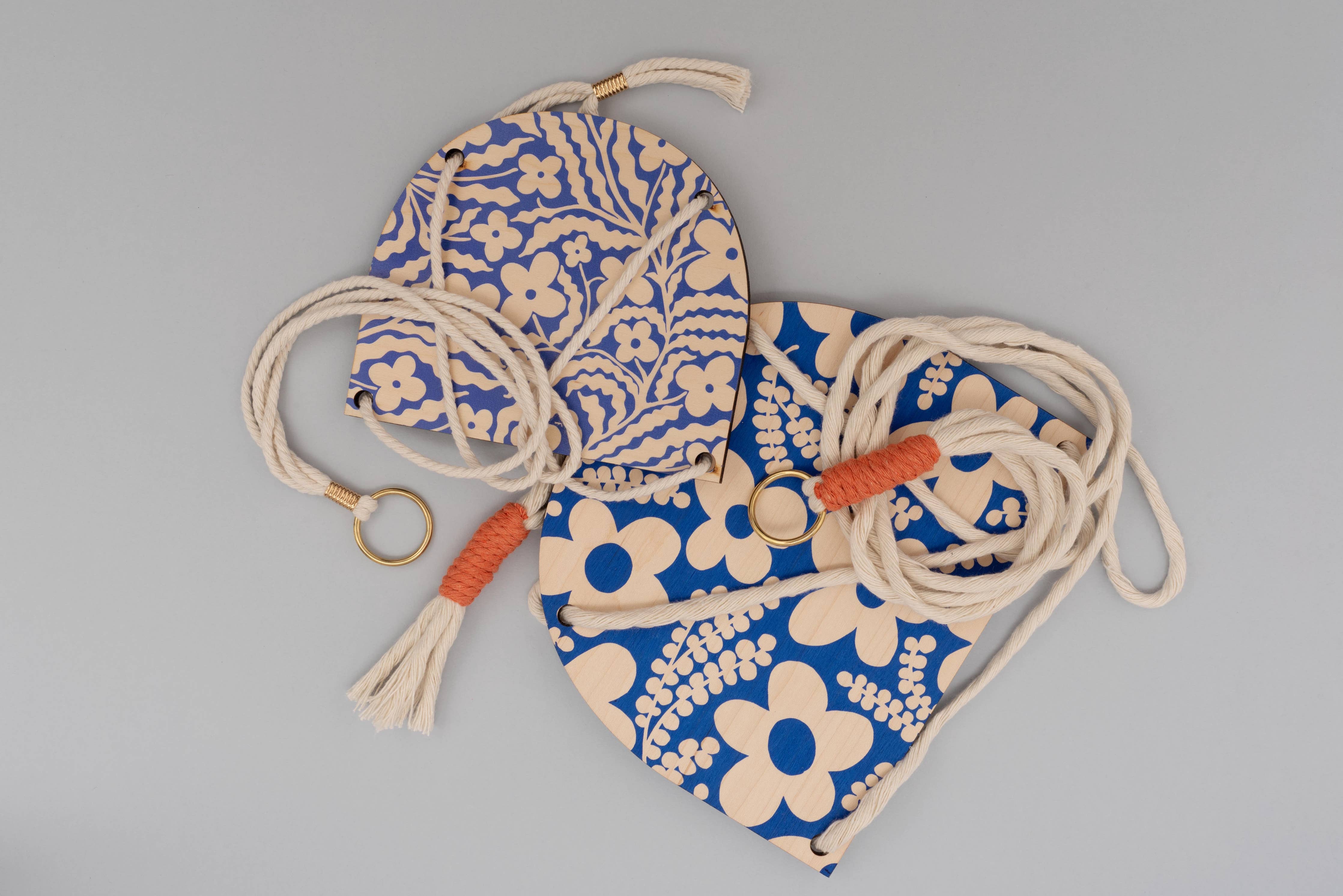 Hanging plant with floral patterns and drawstrings on a grey background.
