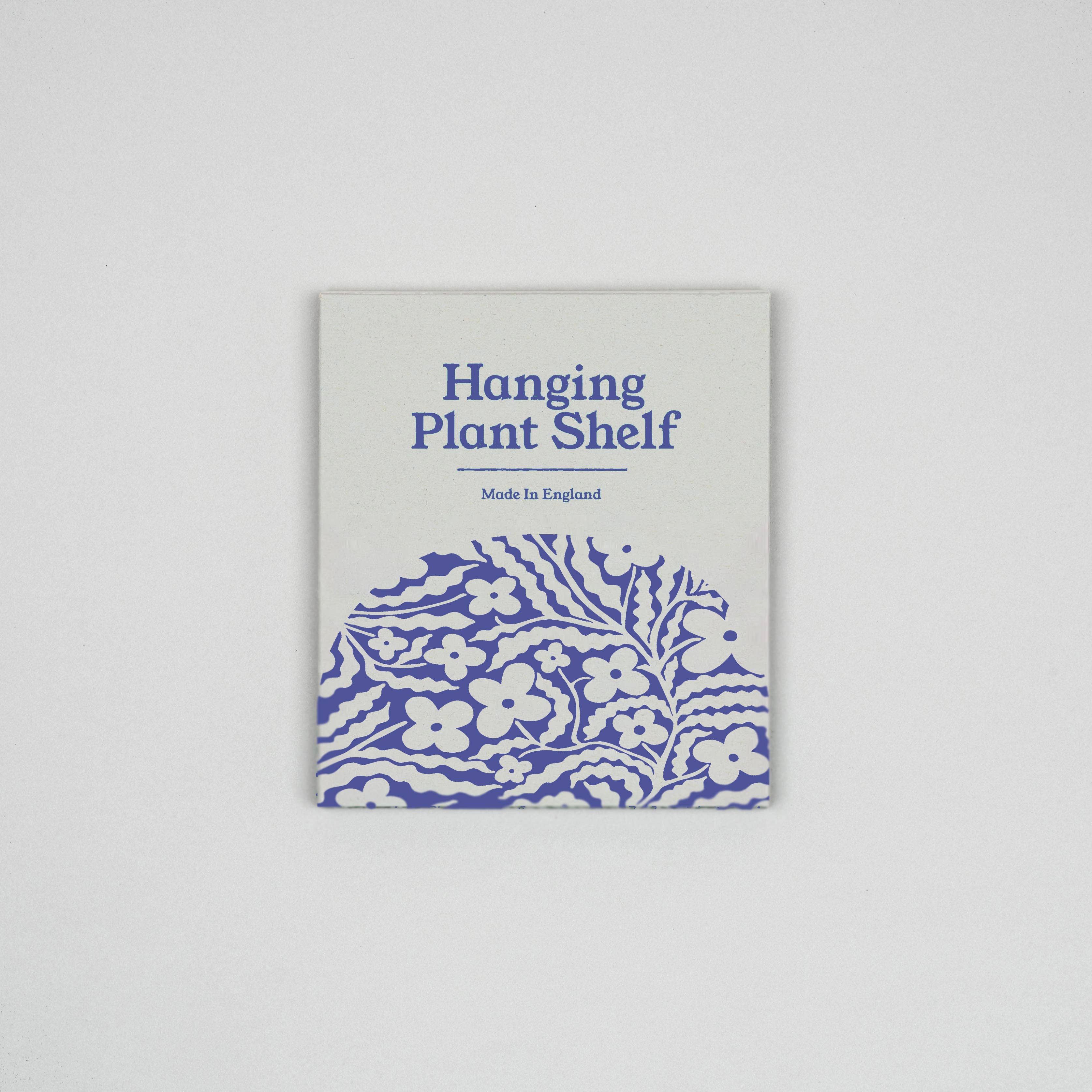 Product packaging for a hanging plant shelf with floral design and text on a grey background.