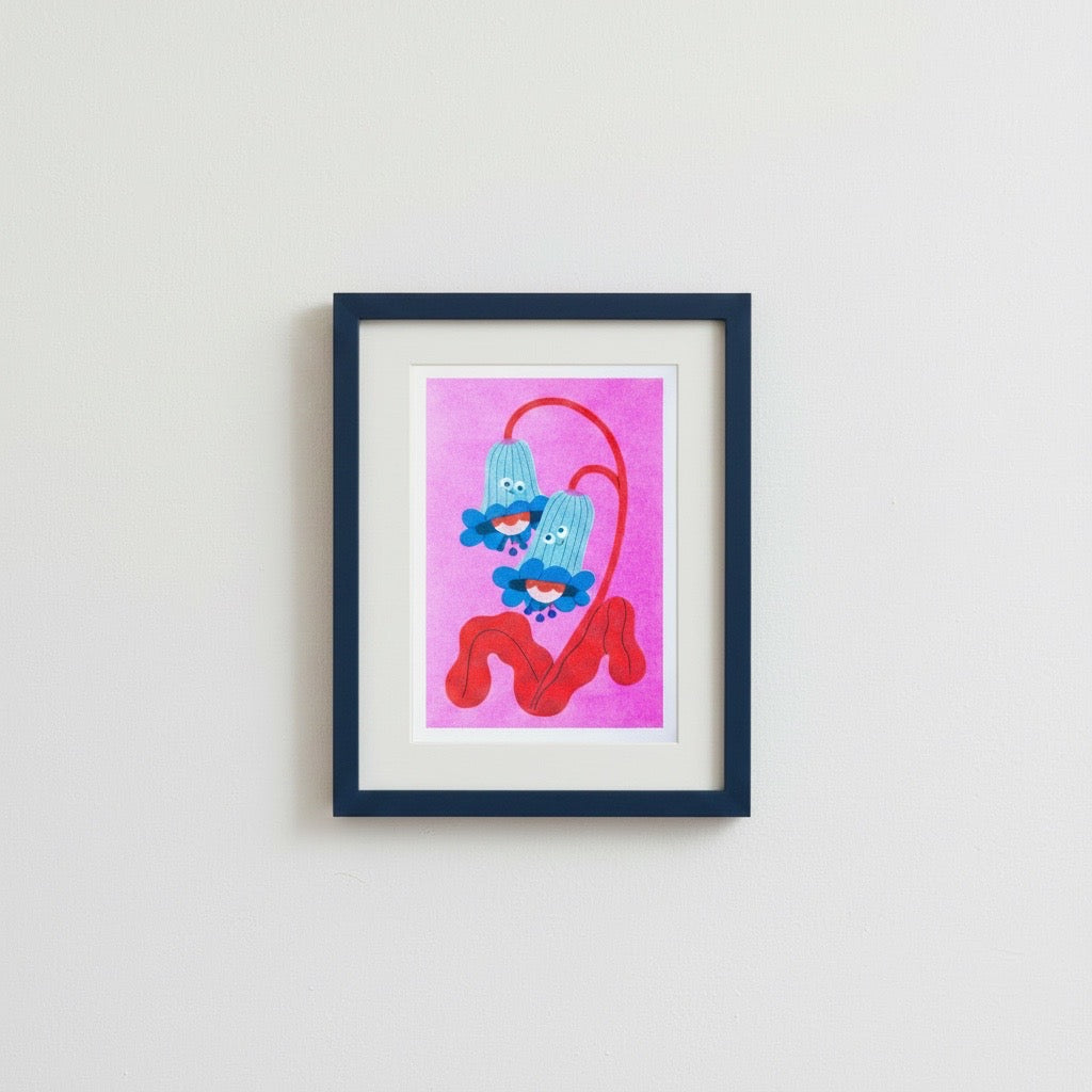 Cartoonish bluebells with red stems on a pink background, framed in a navy blue frame and on a wall.