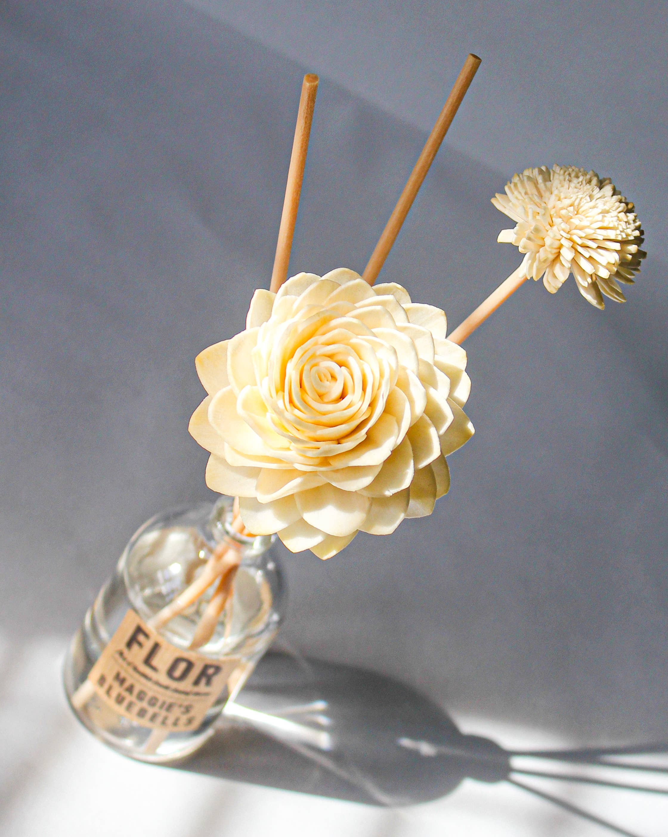 Decorative diffuser with floral elements on a grey background.