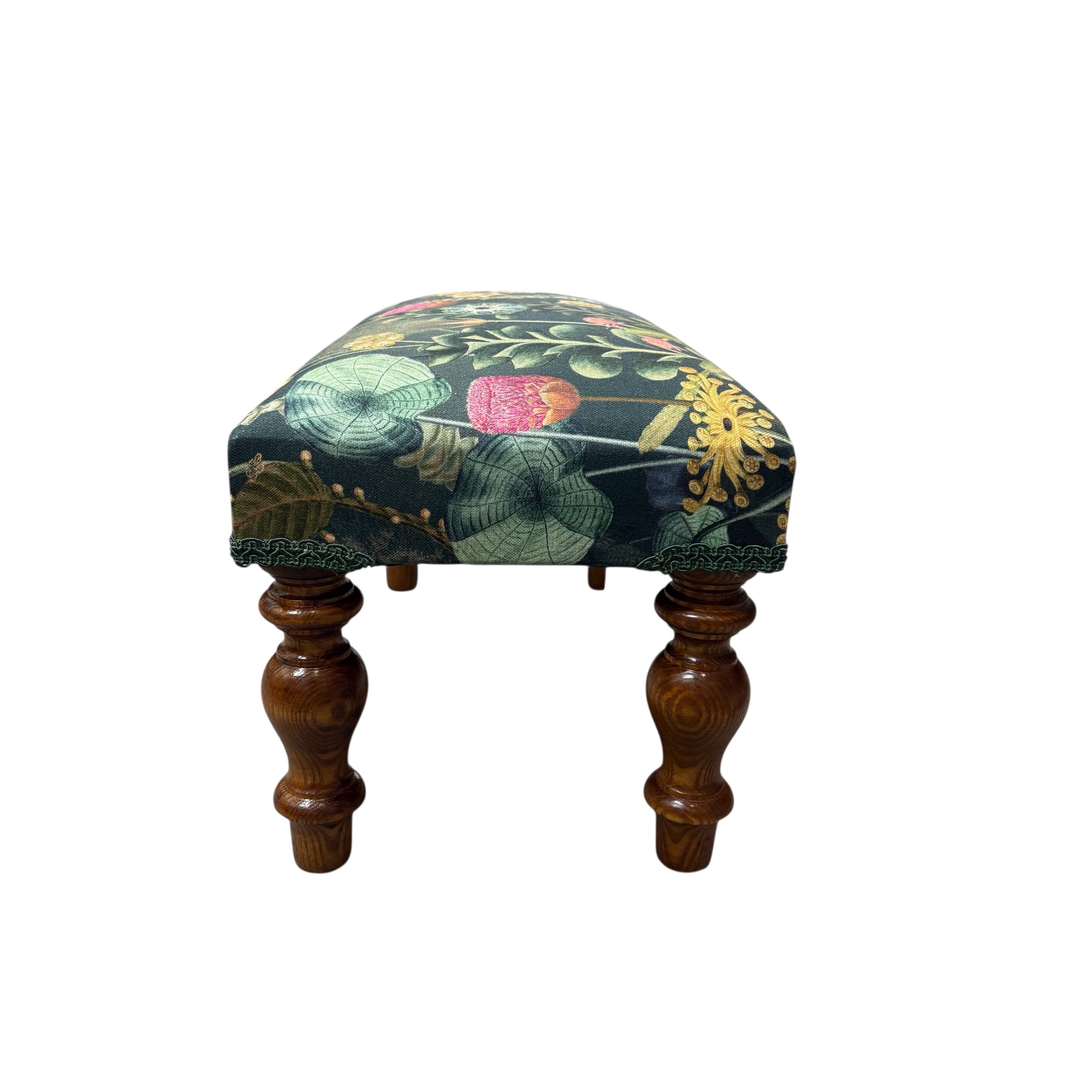 A beautiful hand crafted footstool covered in a dark green cotton featuring a botanical scene in dark green fabric with mahogany stained legs.