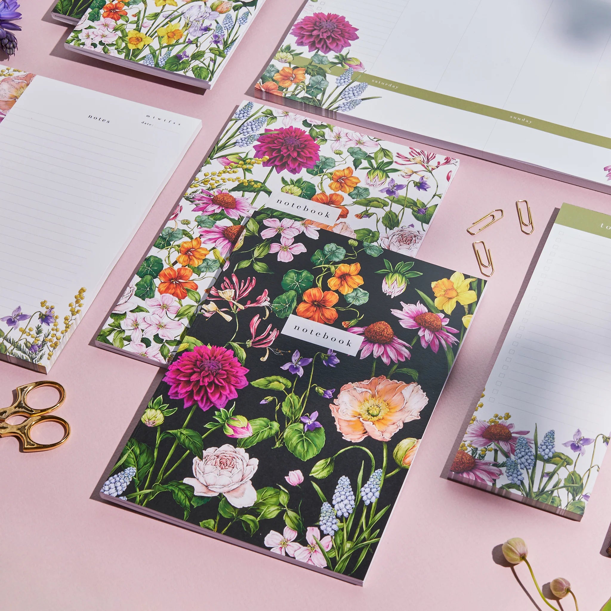 Floral notebooks on a desk surrounded by other stationary.