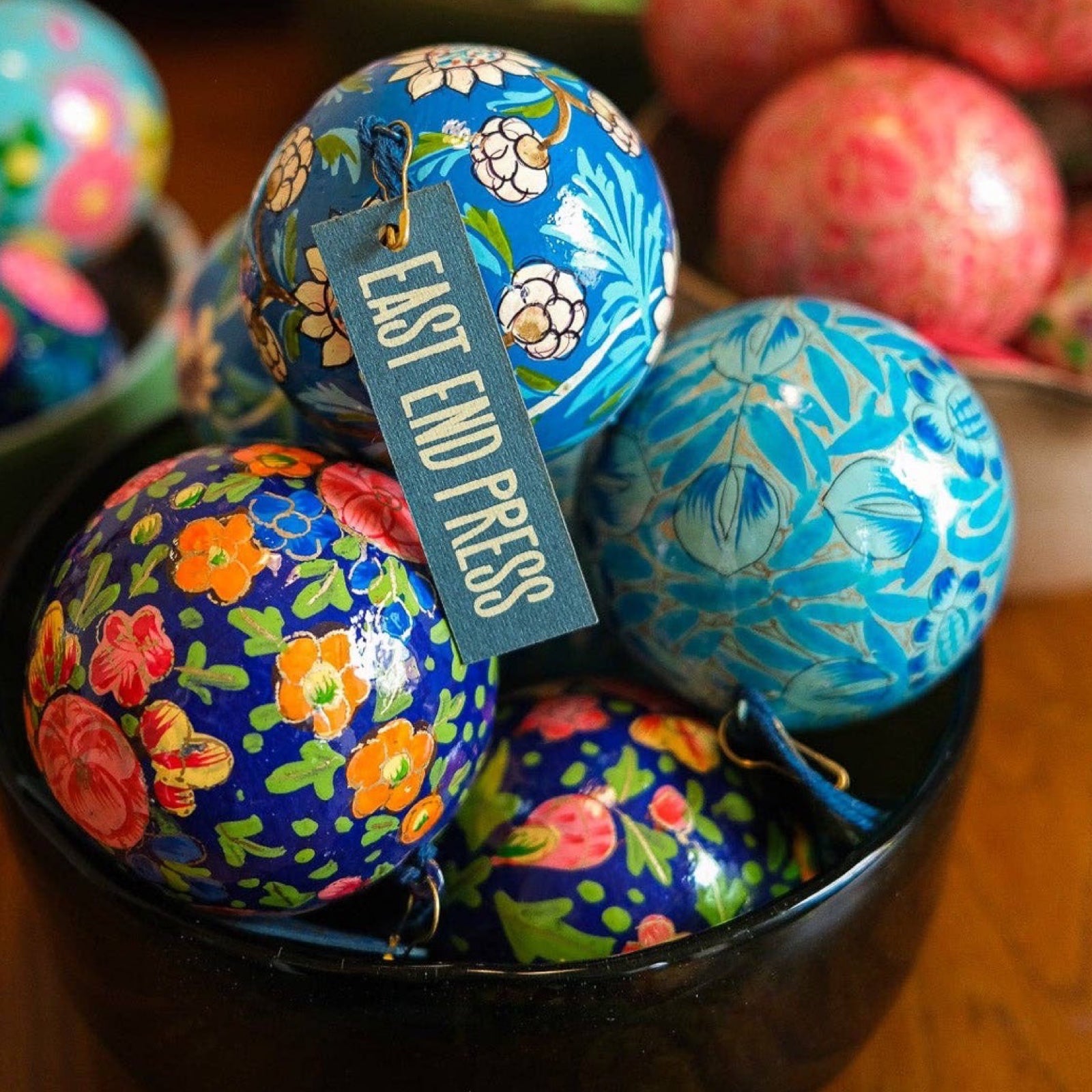 A bowl of round papier mache Christmas baubles in navy, sky blue and cobalt blue.