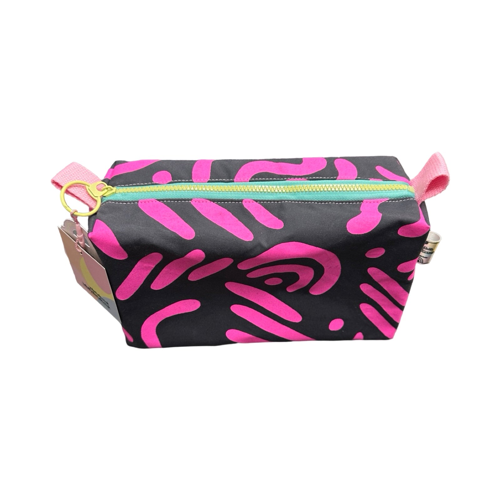 A grey boxy cosmetic bag with a pink abstract design.