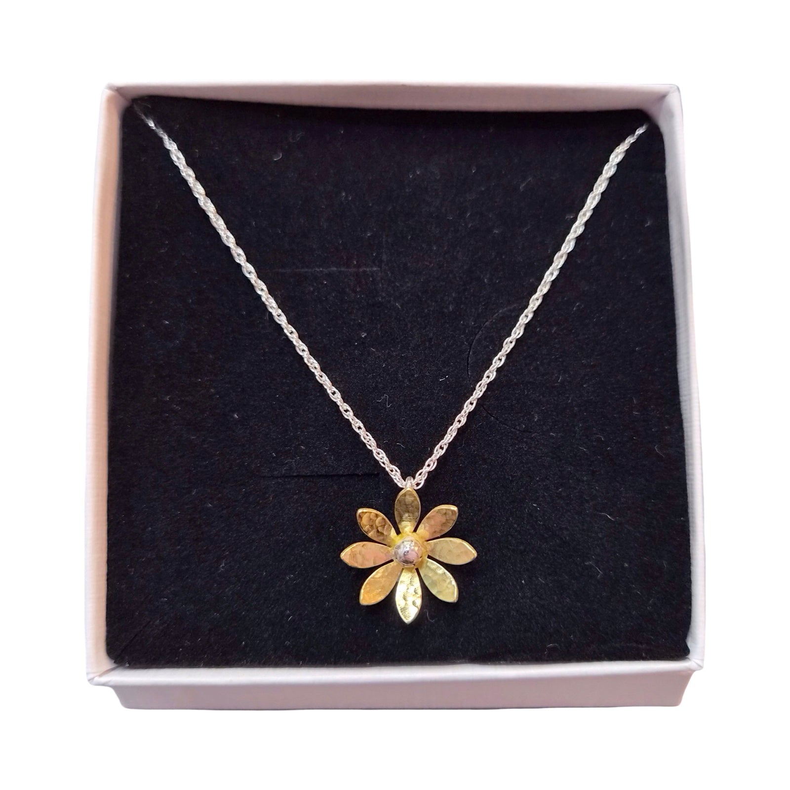 Gold flower pendant necklace in a box on a white background.