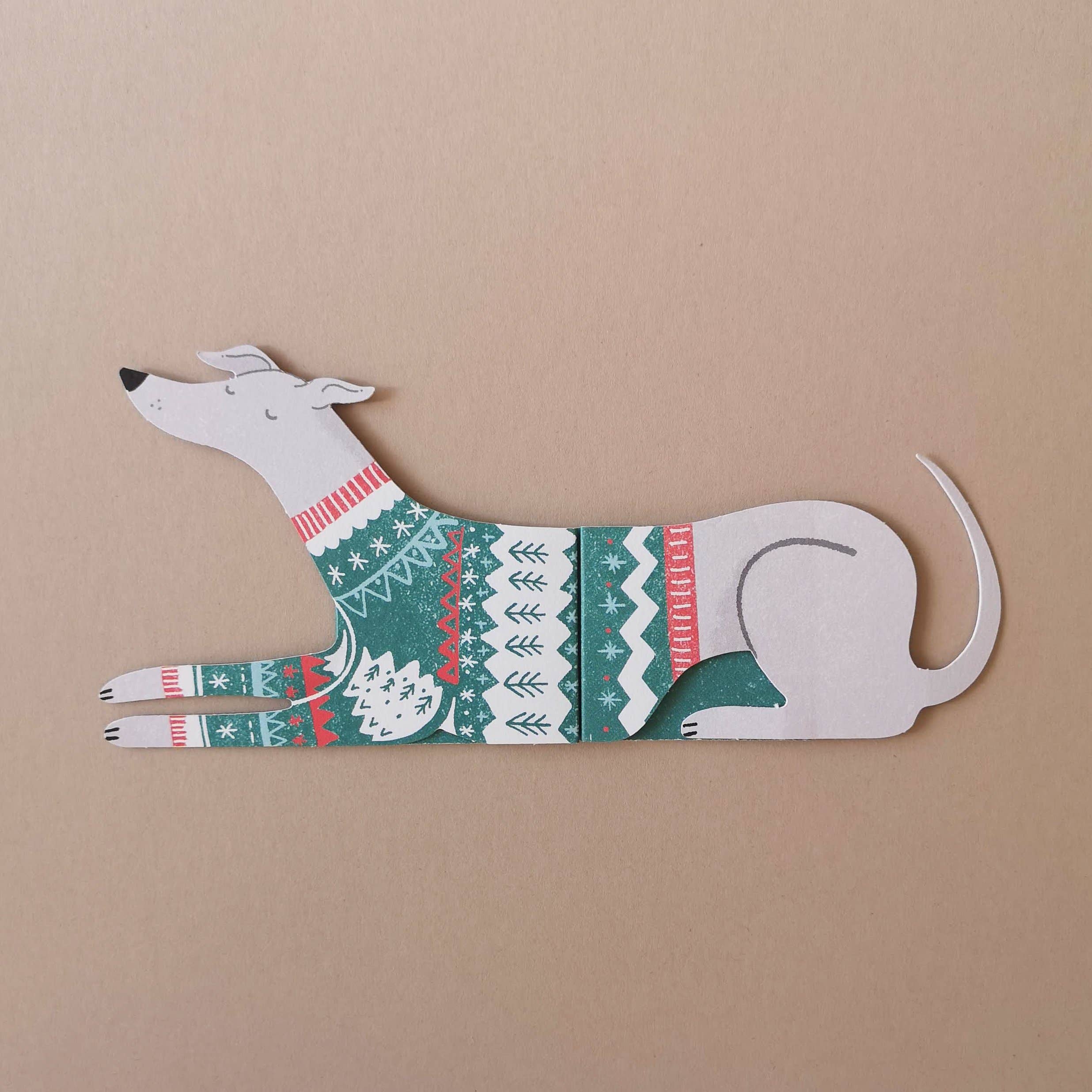 Decorative paper dog with a festive sweater design on a beige background.