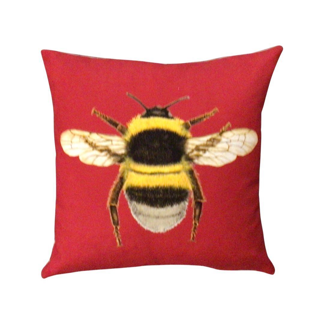 Red velvet cushion with a bumblebee on the front.
