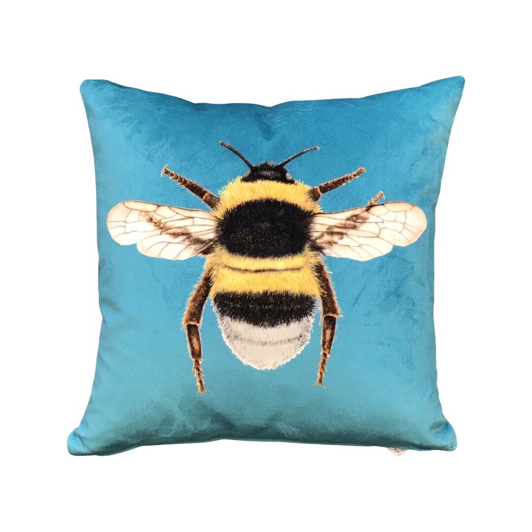 Turquoise velvet cushion with a bumblebee on the front.