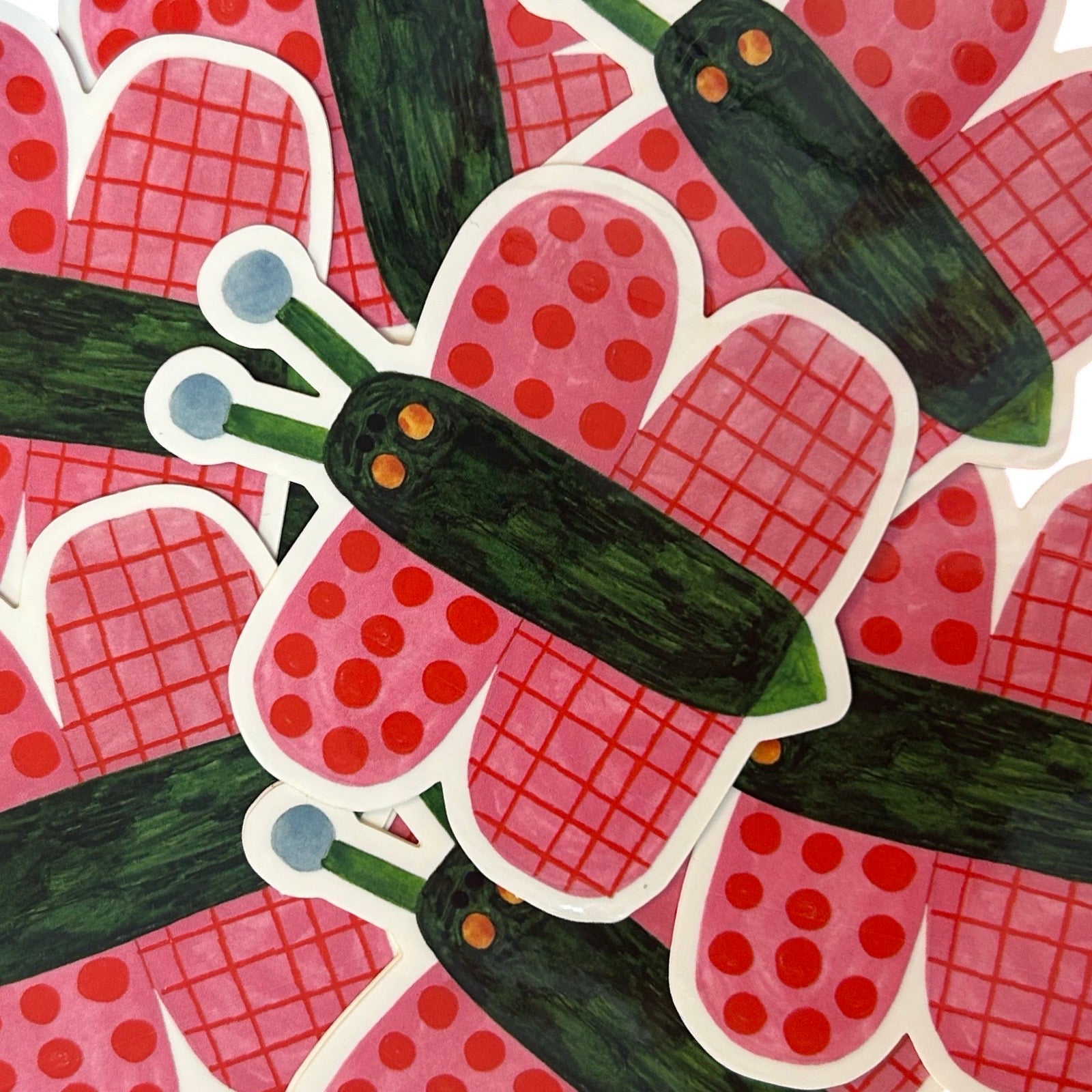A close-up pile of stickers with a butterfly design, with a green body and pink and red wings.