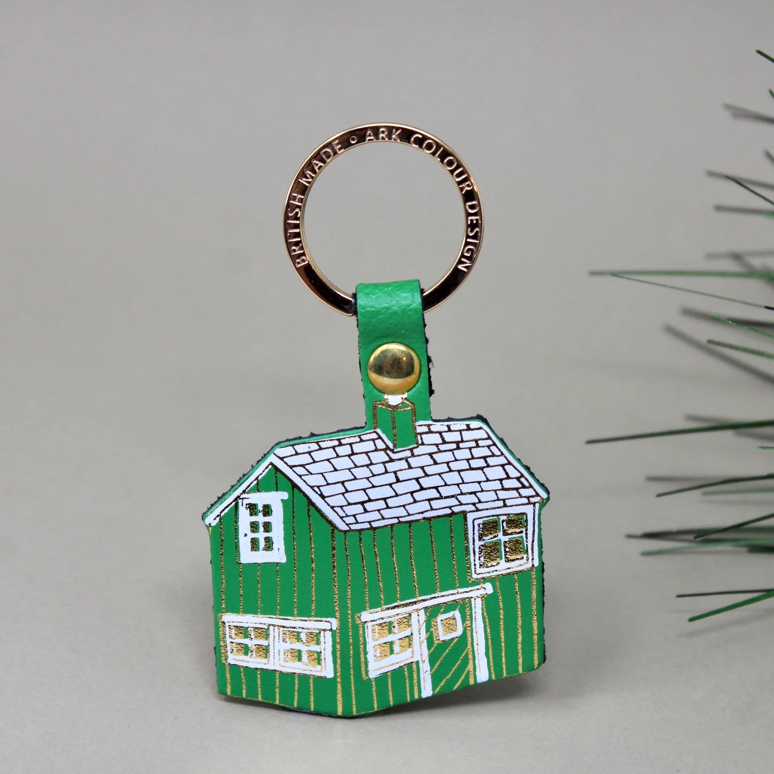 Green house-shaped keyring with a gold accent on a gray background.
