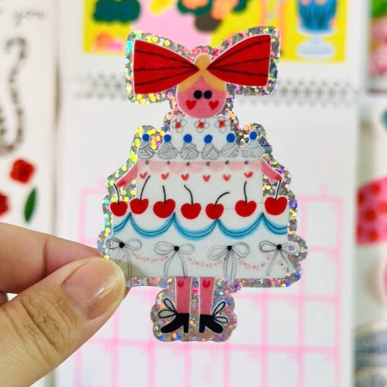 Colourful cake girl held in front of a colourful wall with cartoon-style decorations.