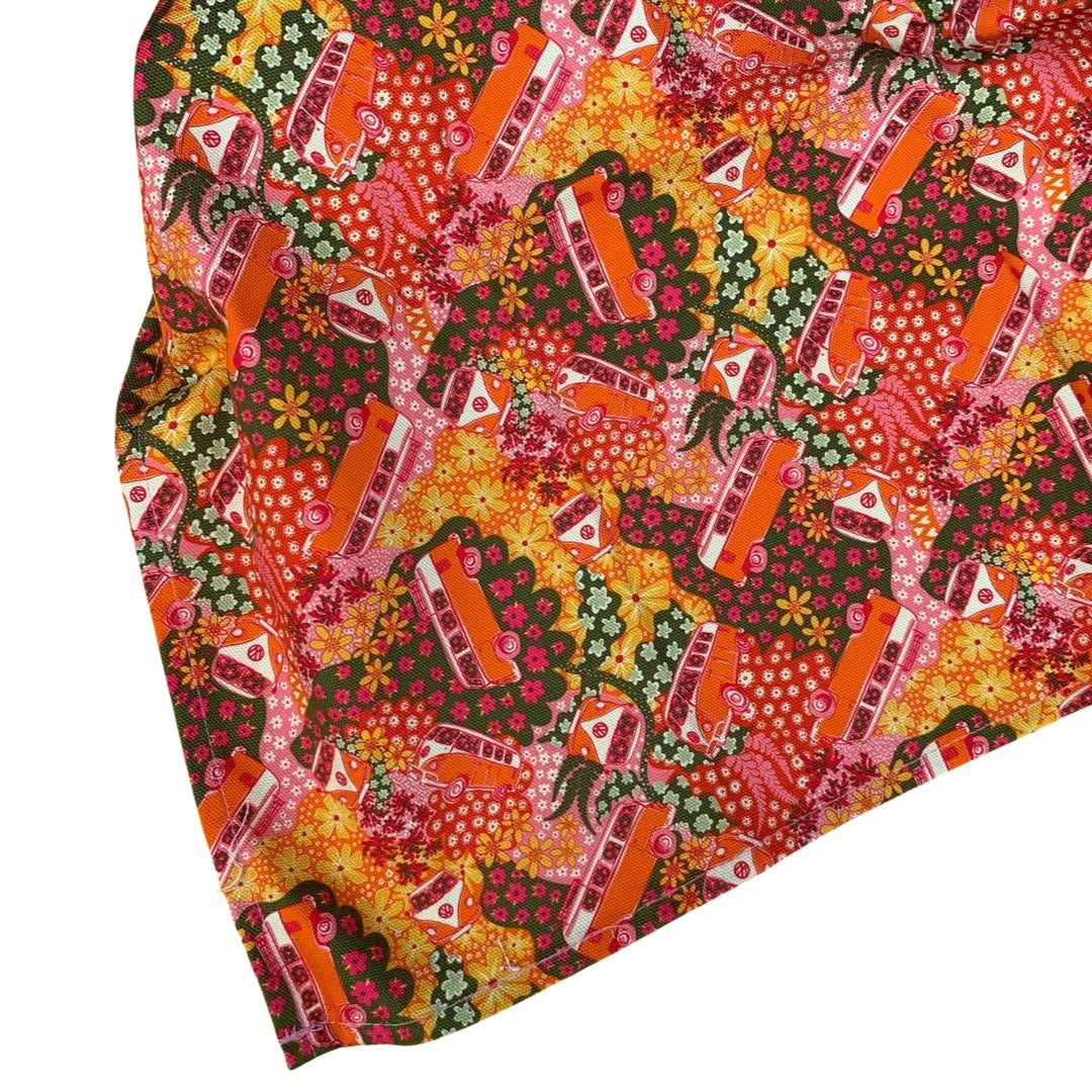 Tea towel with a repeat pattern illustration of an orange and cream VW campervan from the front, the side and angled against a floral backdrop.