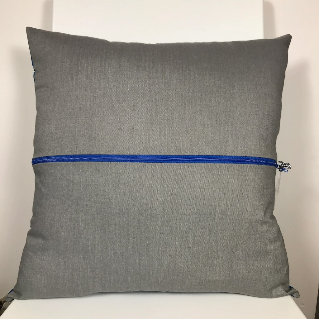 A square cushion cover with a grey cotton back with a blue zip.