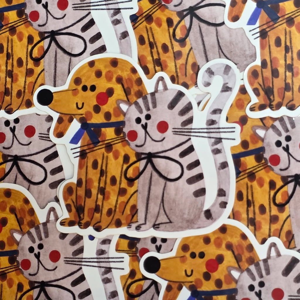This vinyl sticker pile featuring a ginger spotty dog and a grey and black cat both with rosy cheeks.
