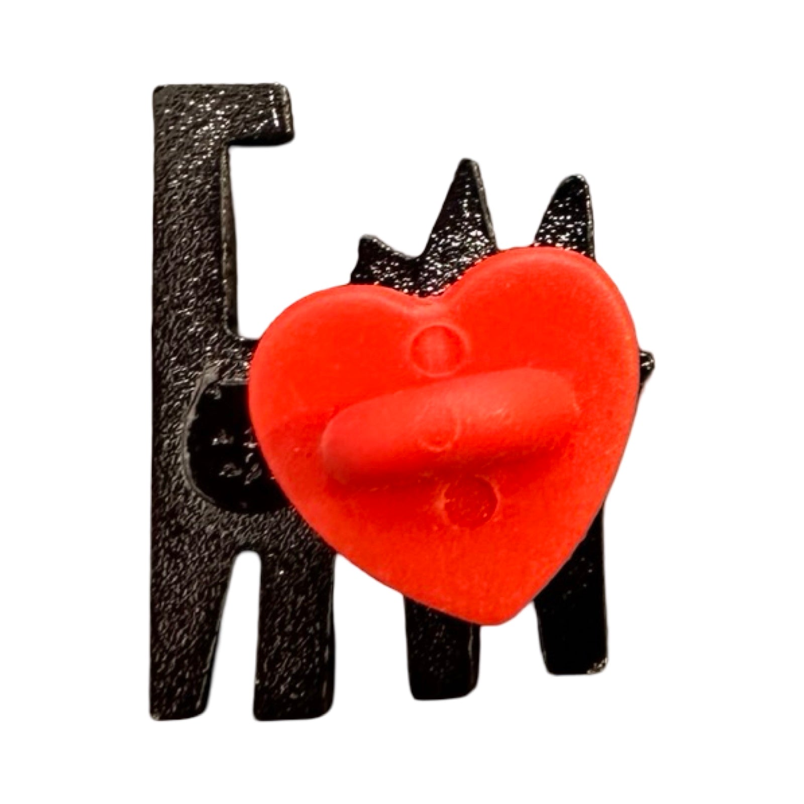 The black back of a cat-shaped enamel pink badge with a red love heart shaped rubber clasp.